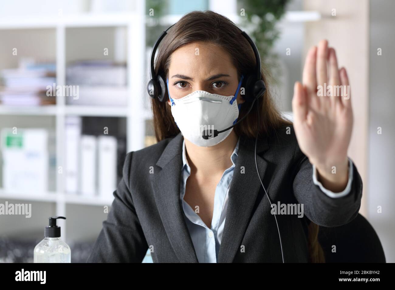 Ernste Telemarketerin Frau Gesturing stoppen Vermeidung covid-19 mit Maske Blick auf Kamera im Büro sitzen Stockfoto