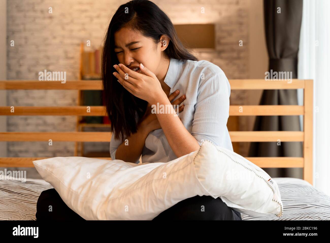 Porträt der 20s junge asiatische Frau mit trockenem Husten im Schlafzimmer zu Hause Stockfoto
