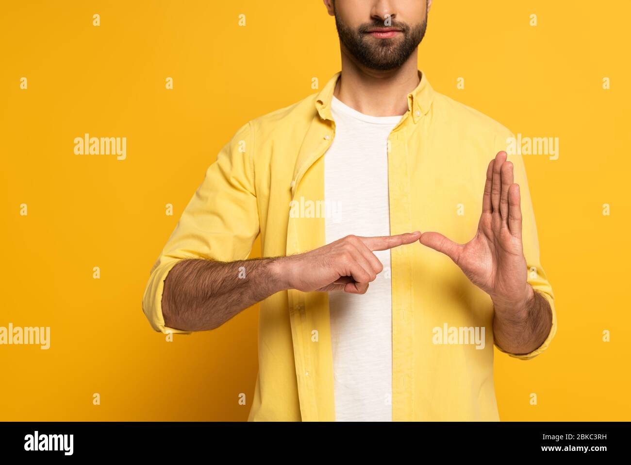 Zugeschnittene Ansicht des Mannes, der Geste von Gebärdensprache auf gelbem Hintergrund zeigt Stockfoto