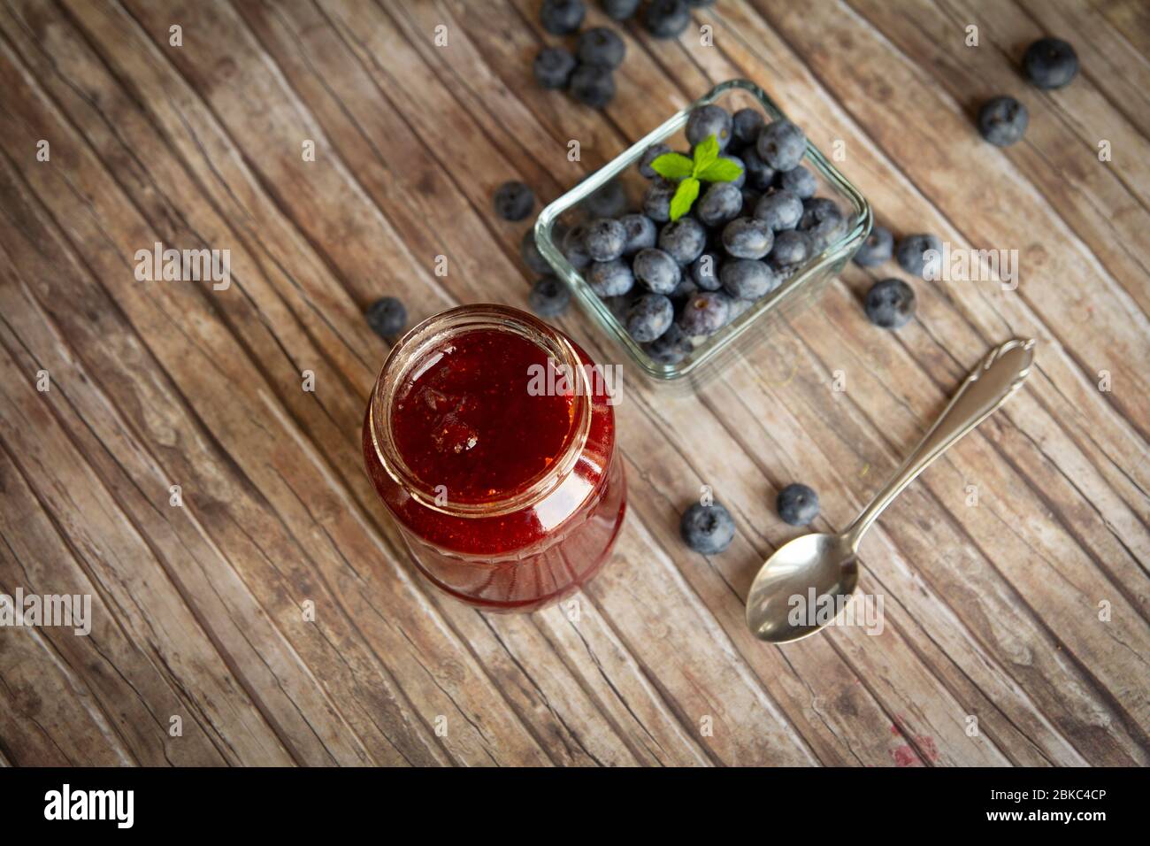 Heidelbeermarmelade mit Beeren auf rustikalem Holztisch Stockfoto