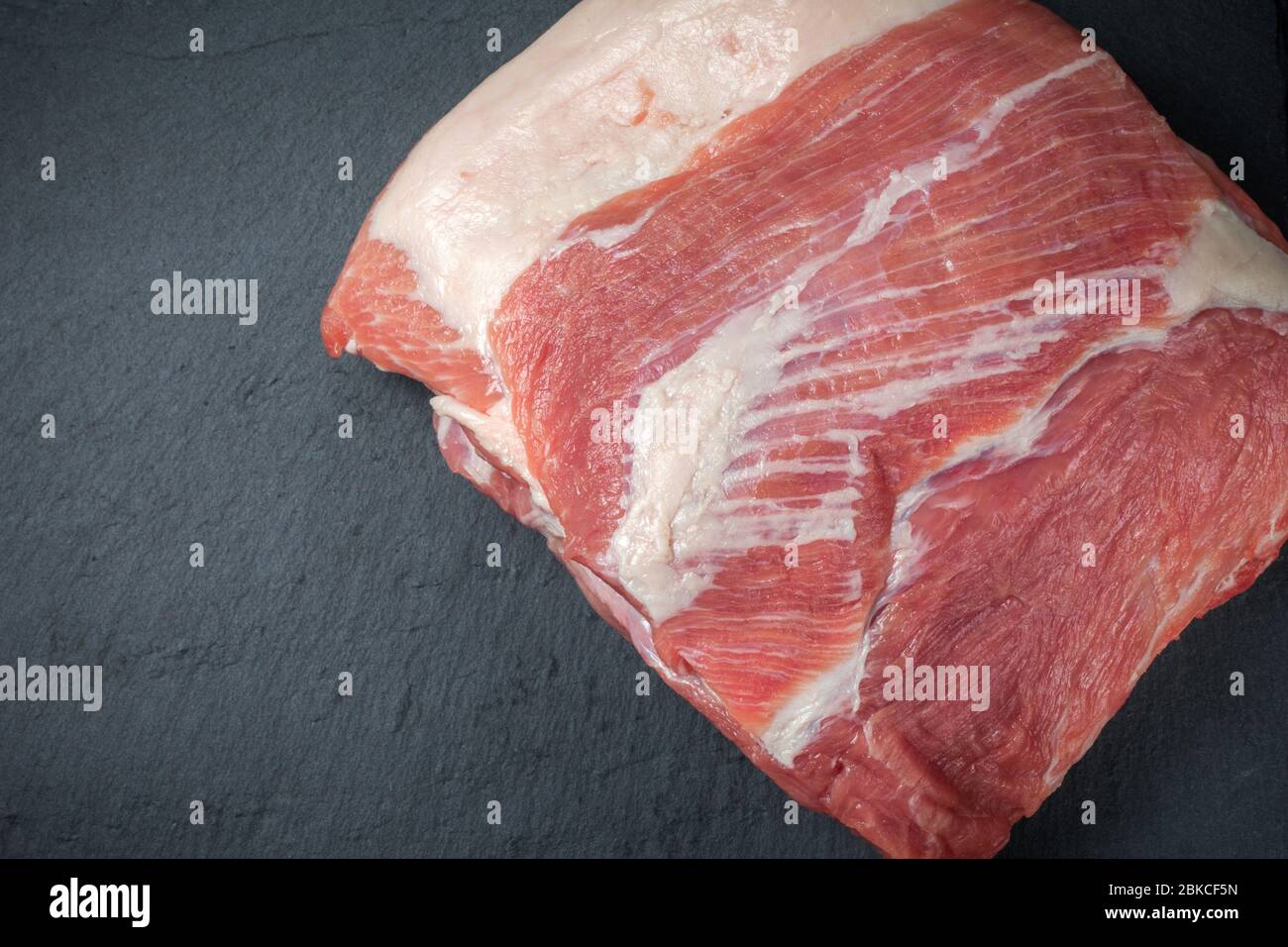 Rohes Schweinefleisch hacken Steak auf einem schwarzen Brett. Schweinehandrikot. Fleisch Stockfoto