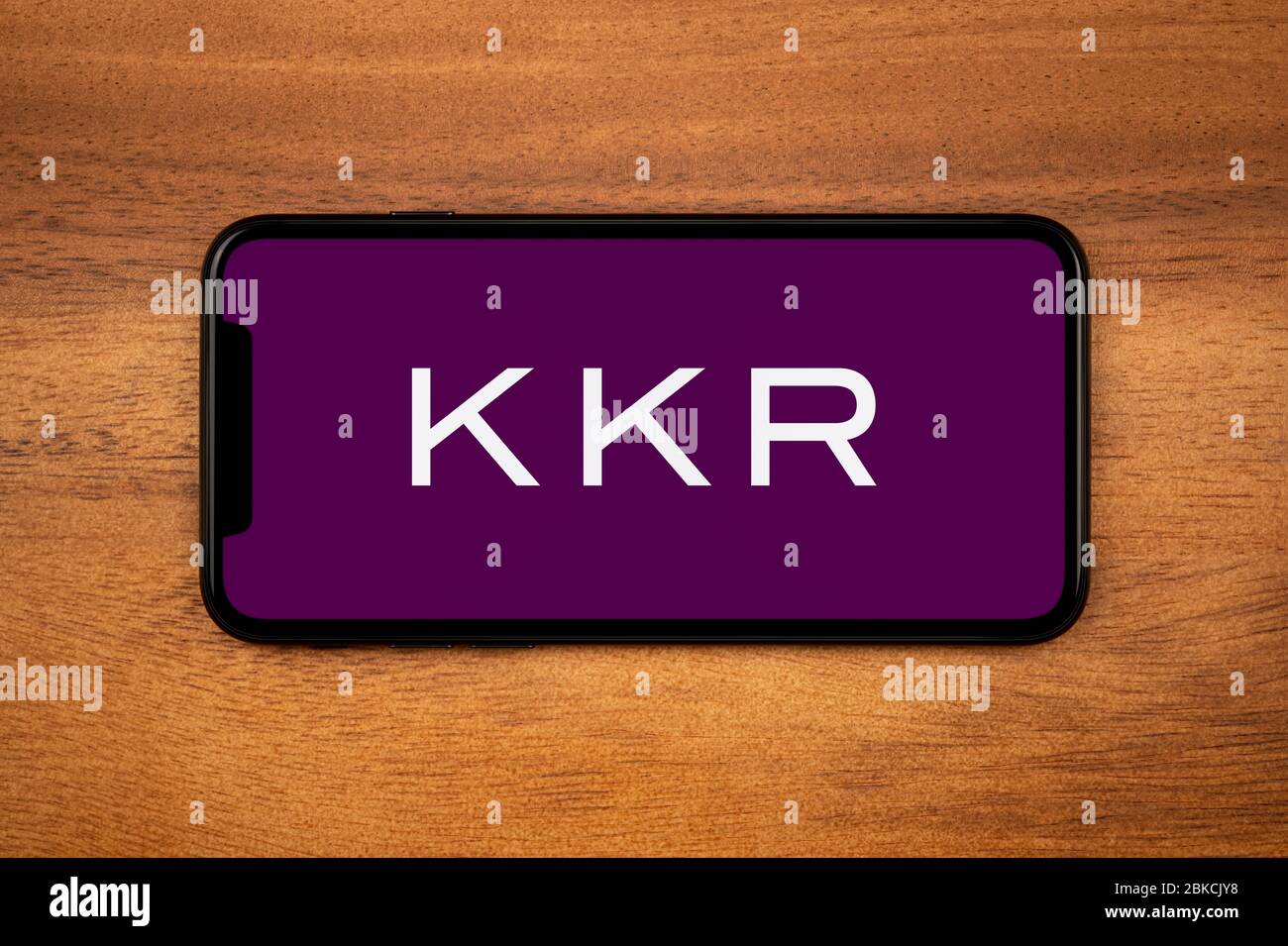 Ein Smartphone mit dem KKR-Logo liegt auf einem einfachen Holztisch (nur redaktionelle Verwendung). Stockfoto