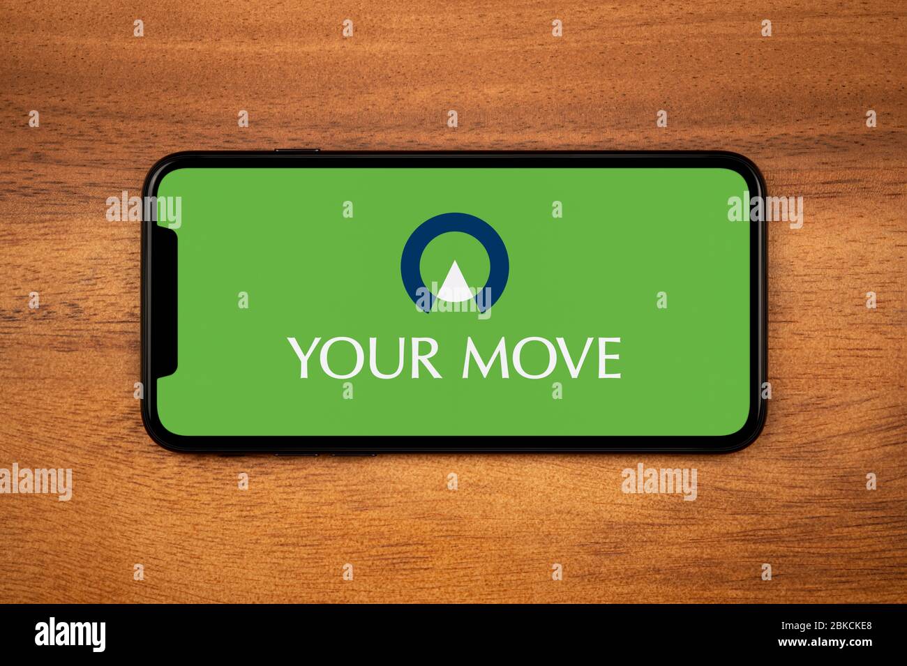 Ein Smartphone mit dem Logo „Your Move“ liegt auf einem einfachen Holztisch (nur für redaktionelle Zwecke). Stockfoto