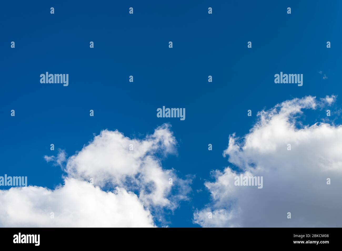 Sonnendurchflutete blauen Himmel Hintergrund mit Kopie Raum und Gruppe von weißen Niederschlagswolken. Landschaftlich reizvolle Aussicht auf dramatische luftige Wolkenlandschaft und fließenden, geschwollenen Cumulus. Stockfoto