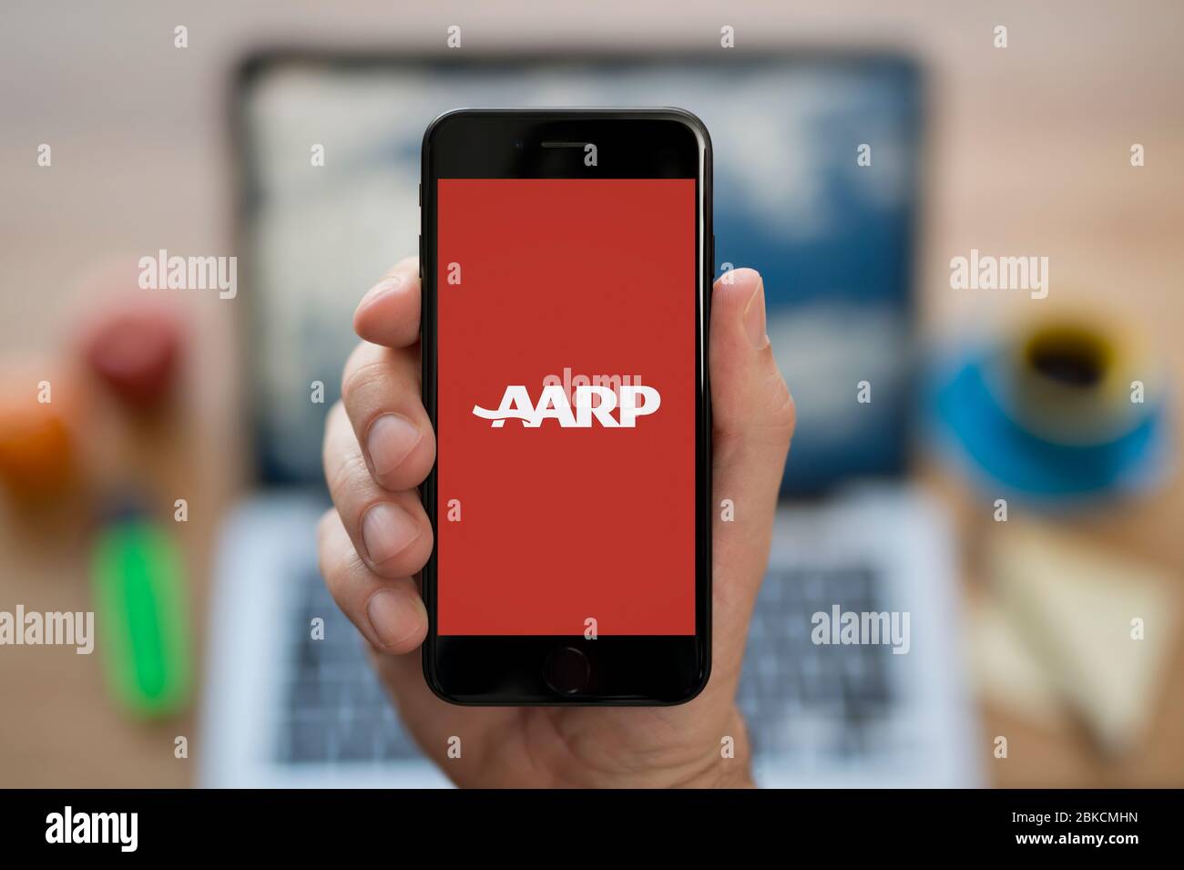 Ein Mann schaut sich sein iPhone an, das das AARP-Logo zeigt (nur redaktionelle Verwendung). Stockfoto