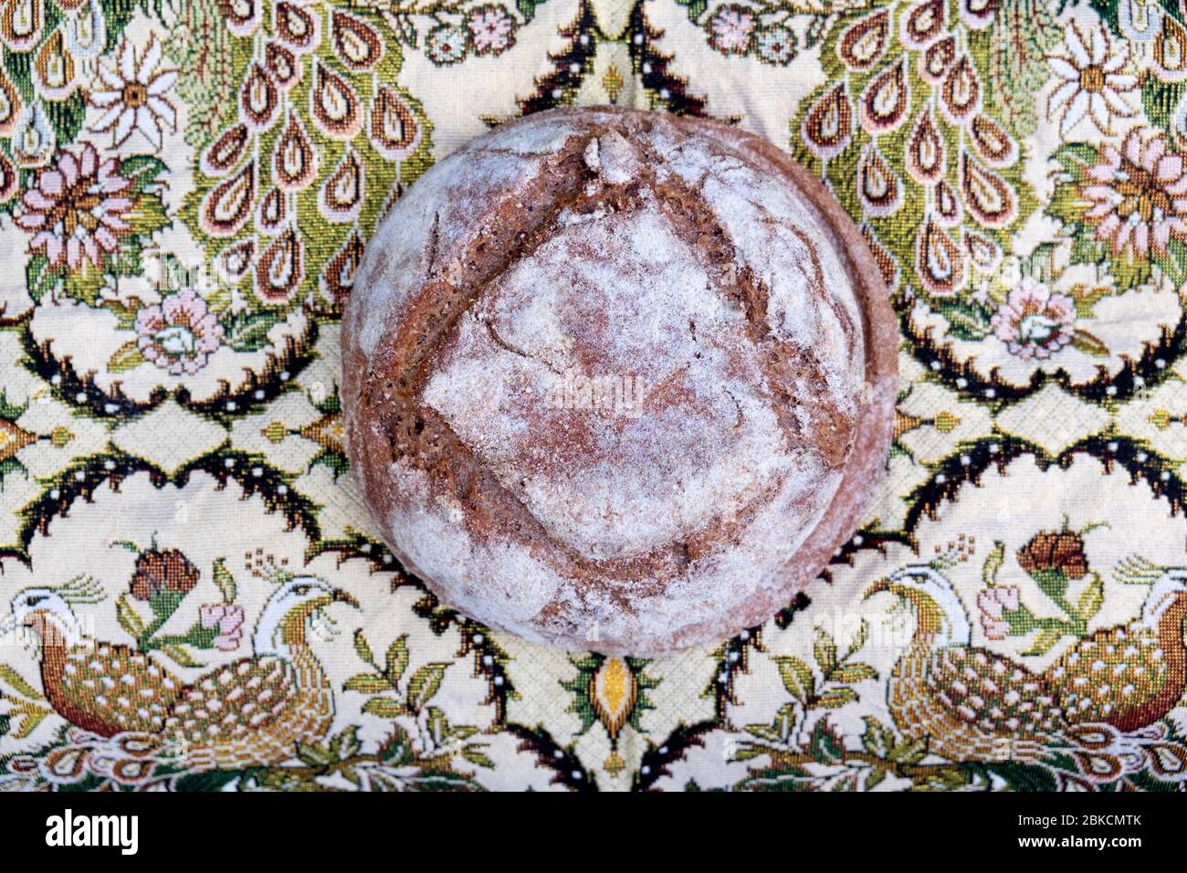 Ein frisch gebackenes Brot aus Roggen und Weizen hausgemachtes Sauerteigbrot von oben auf einem schönen mittelöstlichen Stoffhintergrund UK KATHY DEWITT gesehen Stockfoto