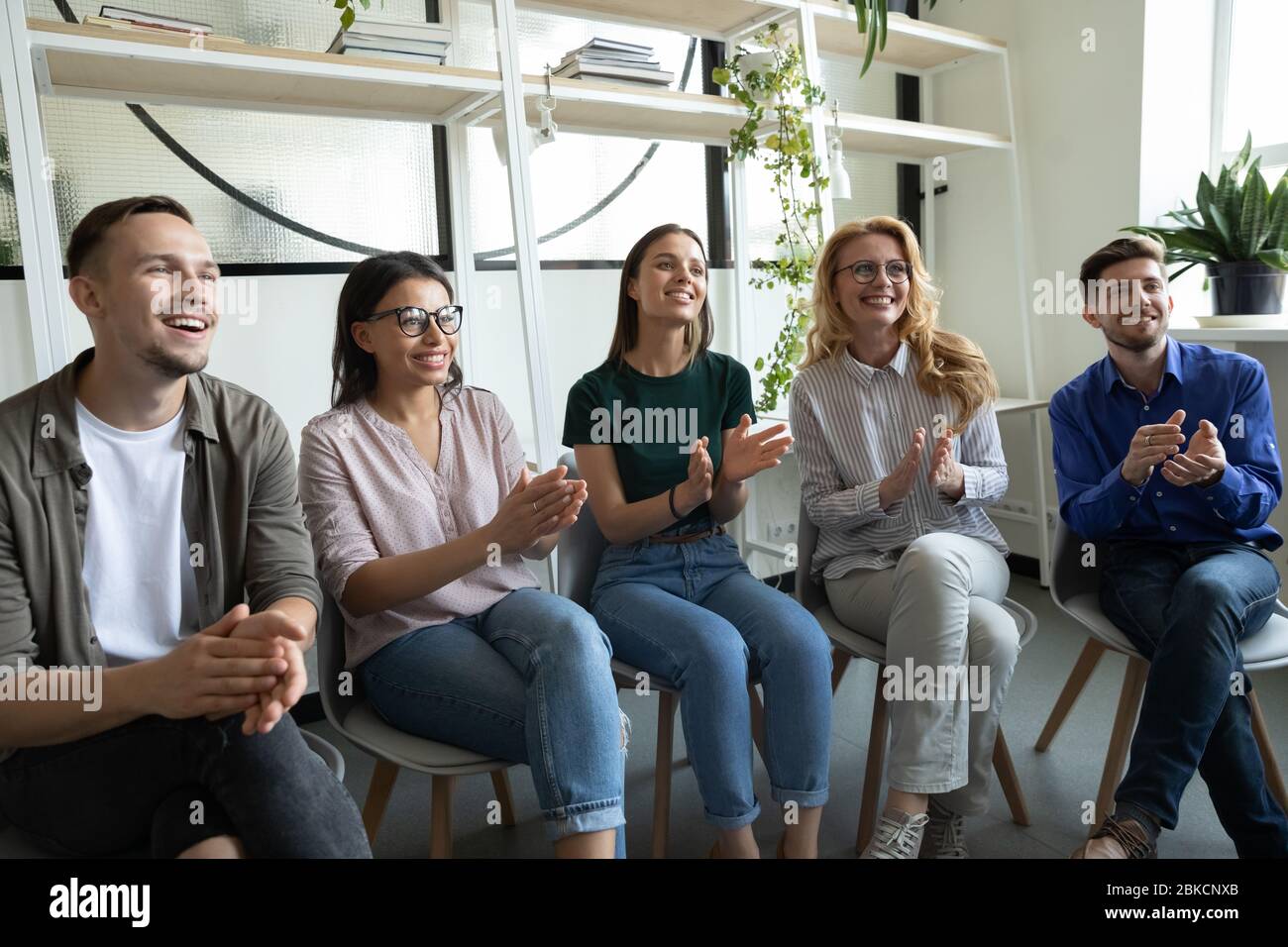 Diverse glückliche Team applaudiert sitzen an der Konferenz klatschen Hände. Stockfoto