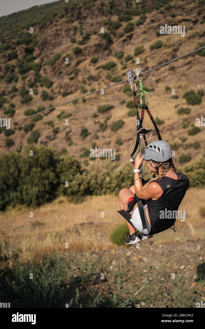 Frau, die an einem Seil hängt. ZIP Line ist eine spannende Abenteuer-Aktivität. Touristen fahren mit der Zip Line durch den Berg. Stockfoto