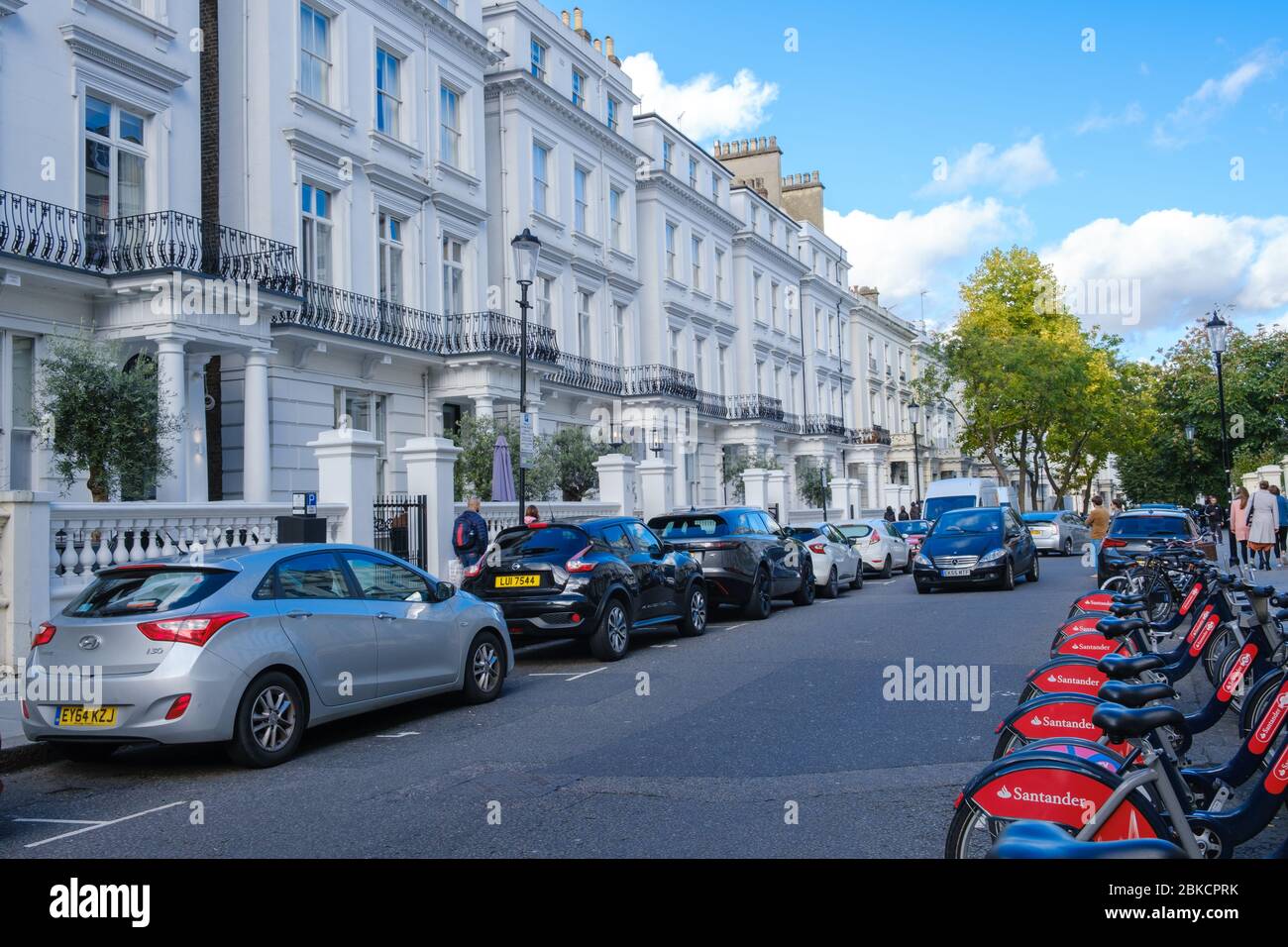 Red Santander Fahrräder zu vermieten geparkt außerhalb weißen Stadthäusern am südlichen Ende der Pembridge Gardens, mit Blick auf Norden, Notting Hill, West London, England, Großbritannien Stockfoto