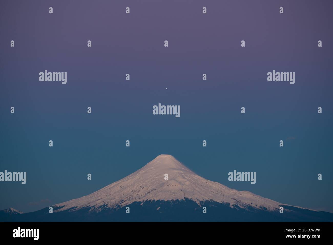 Planet Jupiter, der während der blauen Stunde nach Sonnenuntergang mit dem Gipfel des Osorno-Vulkans ausgerichtet war Stockfoto