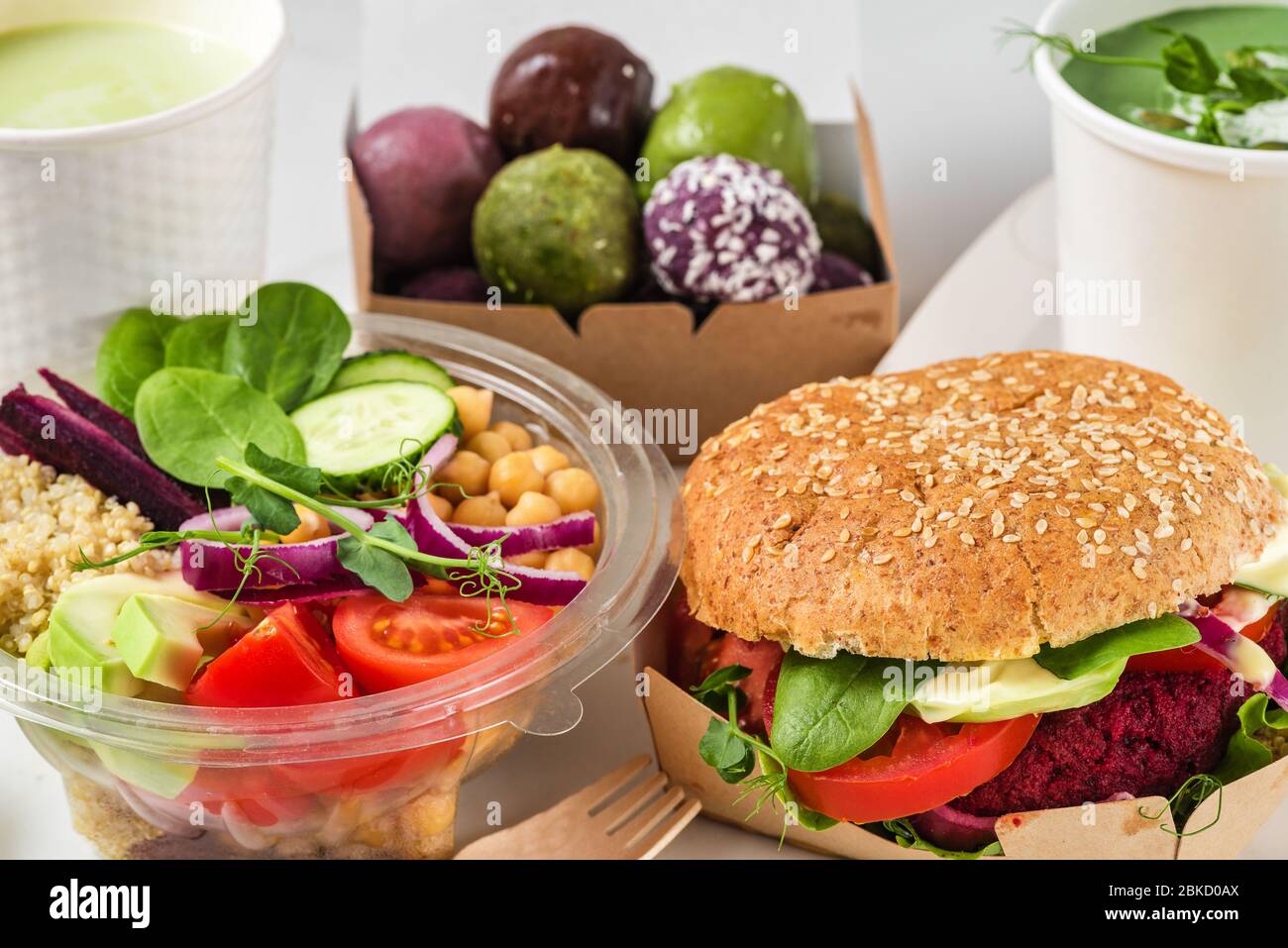 Gesunde vegane Lebensmittel liefern. Buddha Schüssel Salat, Burger, Suppe, Dessert und Matcha Latte in Kisten und Tassen verpackt. Restaurant-Menü zum Mitnehmen Stockfoto