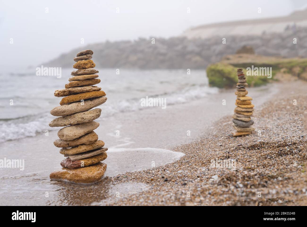 Steinpyramide auf Sand symbolisiert Zen, Harmonie, Gleichgewicht. Positive Energie. Ozean im Hintergrund Stockfoto