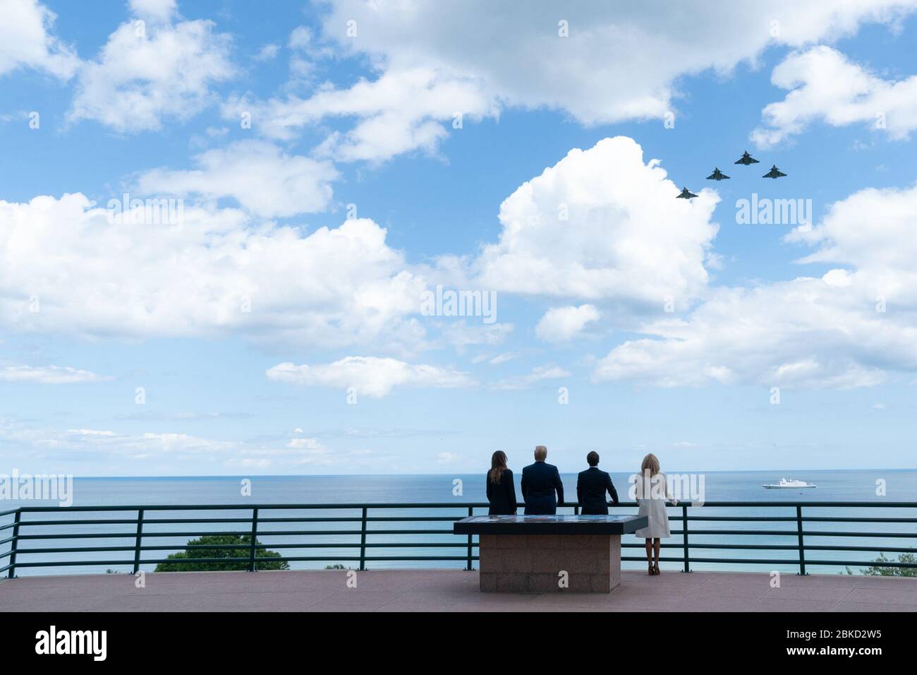 Am 6. Juni 2019 beobachteten Präsident Trump und First Lady Melania Trump zusammen mit dem französischen Präsidenten Emmanuel Macron und seiner Frau Brigitte Macron einen Überflug von F-15-Flugzeugen auf dem amerikanischen Friedhof in der Normandie, anlässlich des 75. Jahrestages des D-Day. Stockfoto