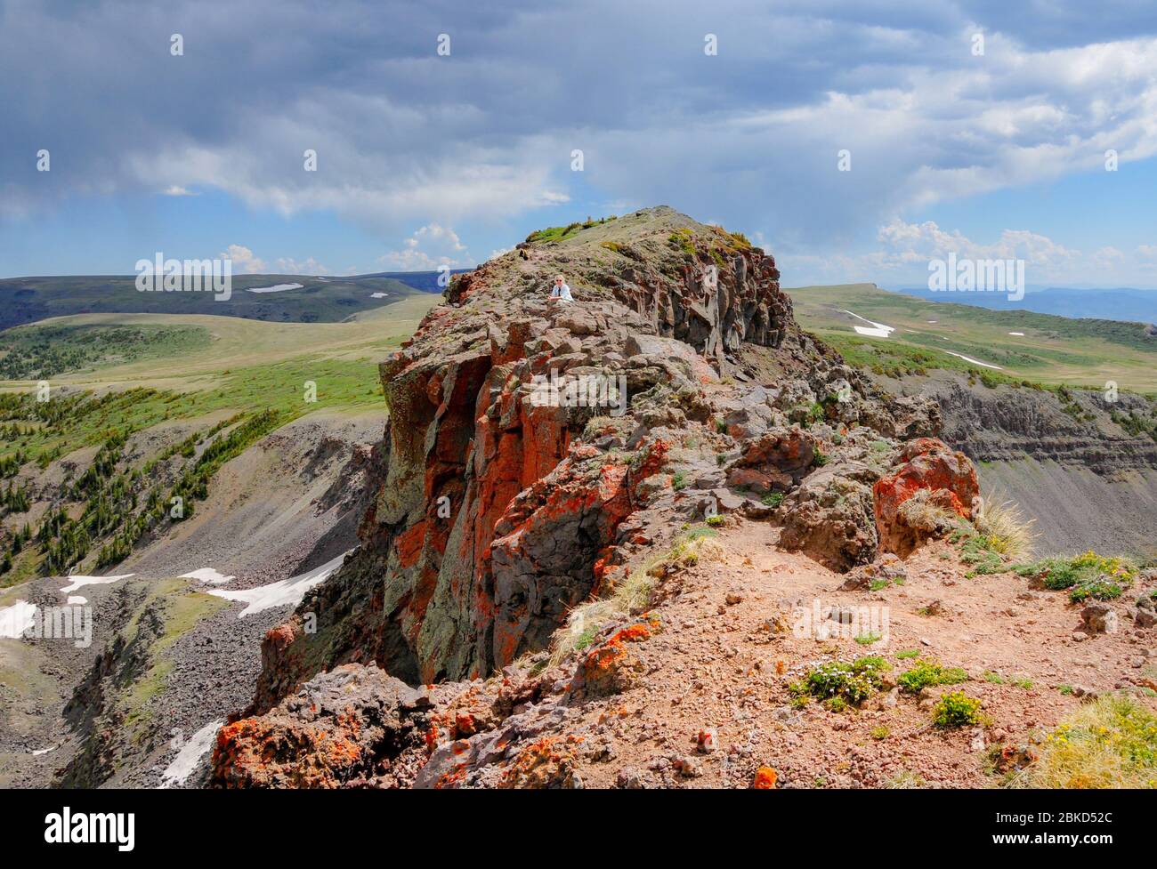 Panoramablick auf eine Wanderfrau auf einer Colorado Klippe, umgeben von einem grünen Tal. Modellversion Stockfoto