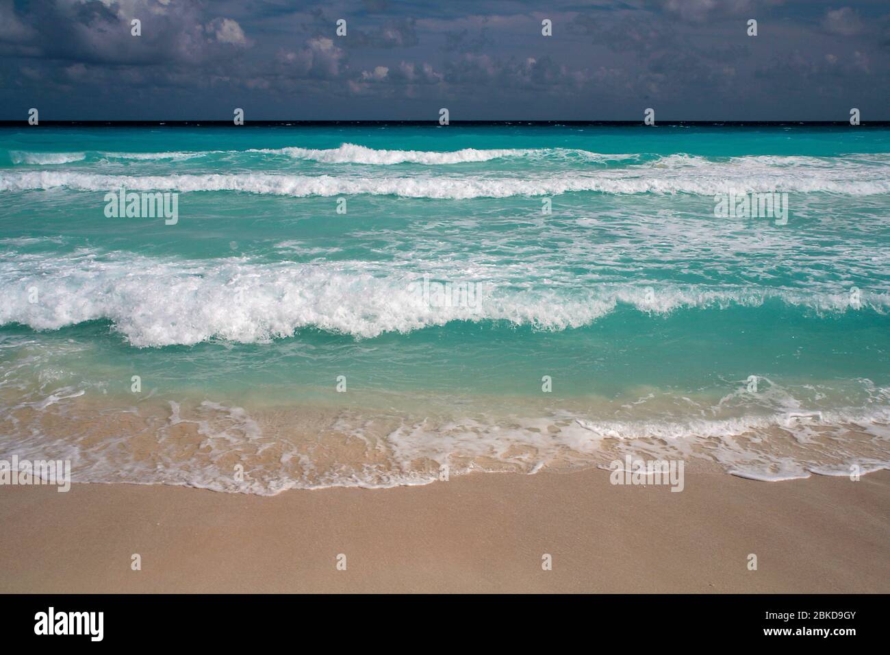 Türkisfarbene Meereswellen, die auf den Sandstrand stürzen Stockfoto