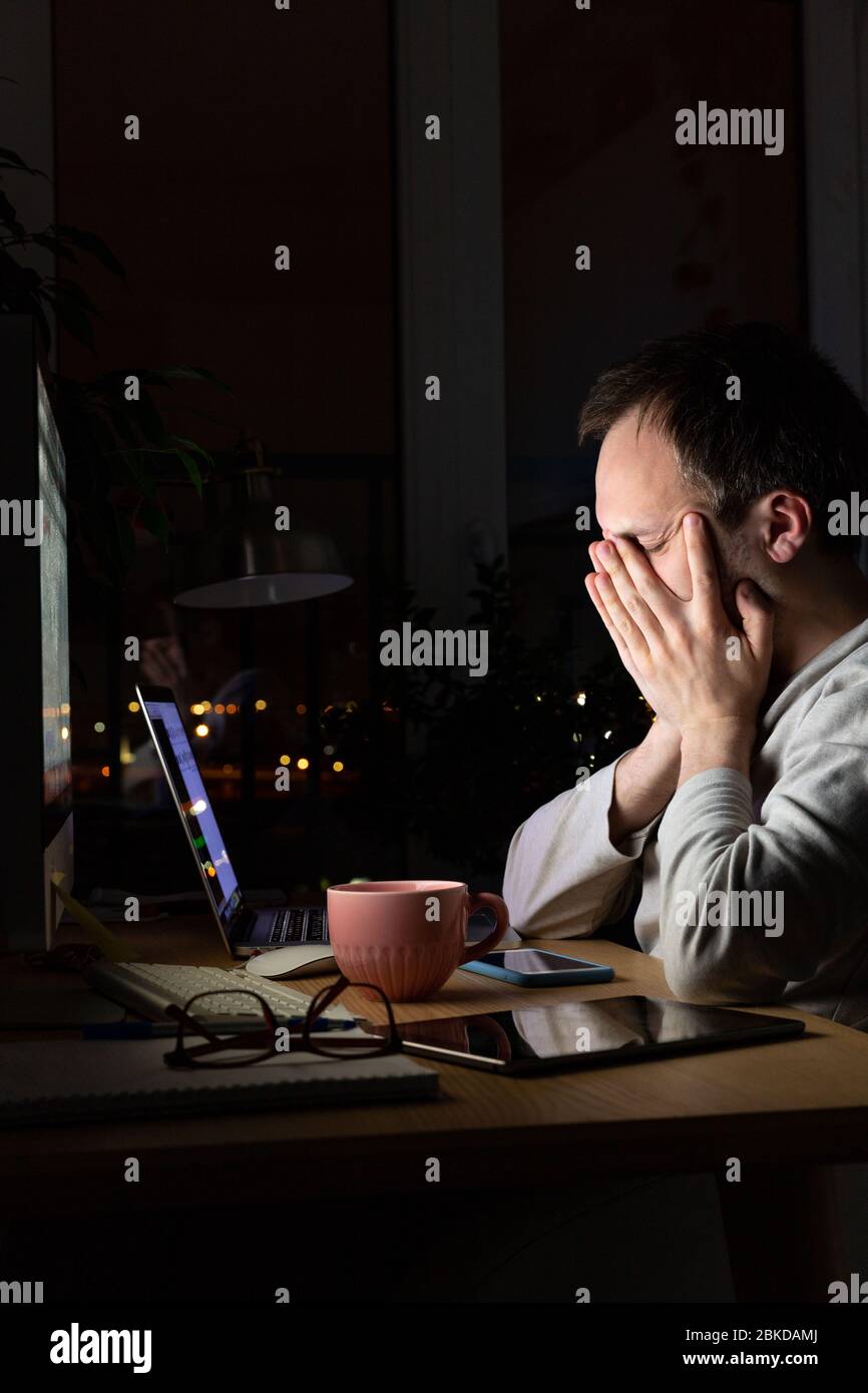 Müde Freelancer Mann reibt sich die Augen, sitzt an einem Desktop-PC / Laptop spät in der Nacht, schläft aus Müdigkeit. Stockfoto