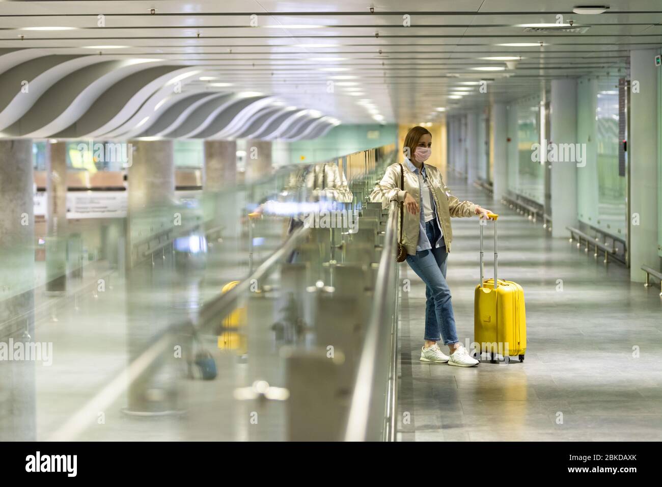 Frau mit Gepäck am leerstehenden Flughafenterminal aufgrund von Einschränkungen für Reisen mit Coronavirus Pandemic/Covid-19-Ausbruch. Flugstornierung. Reiserindu Stockfoto