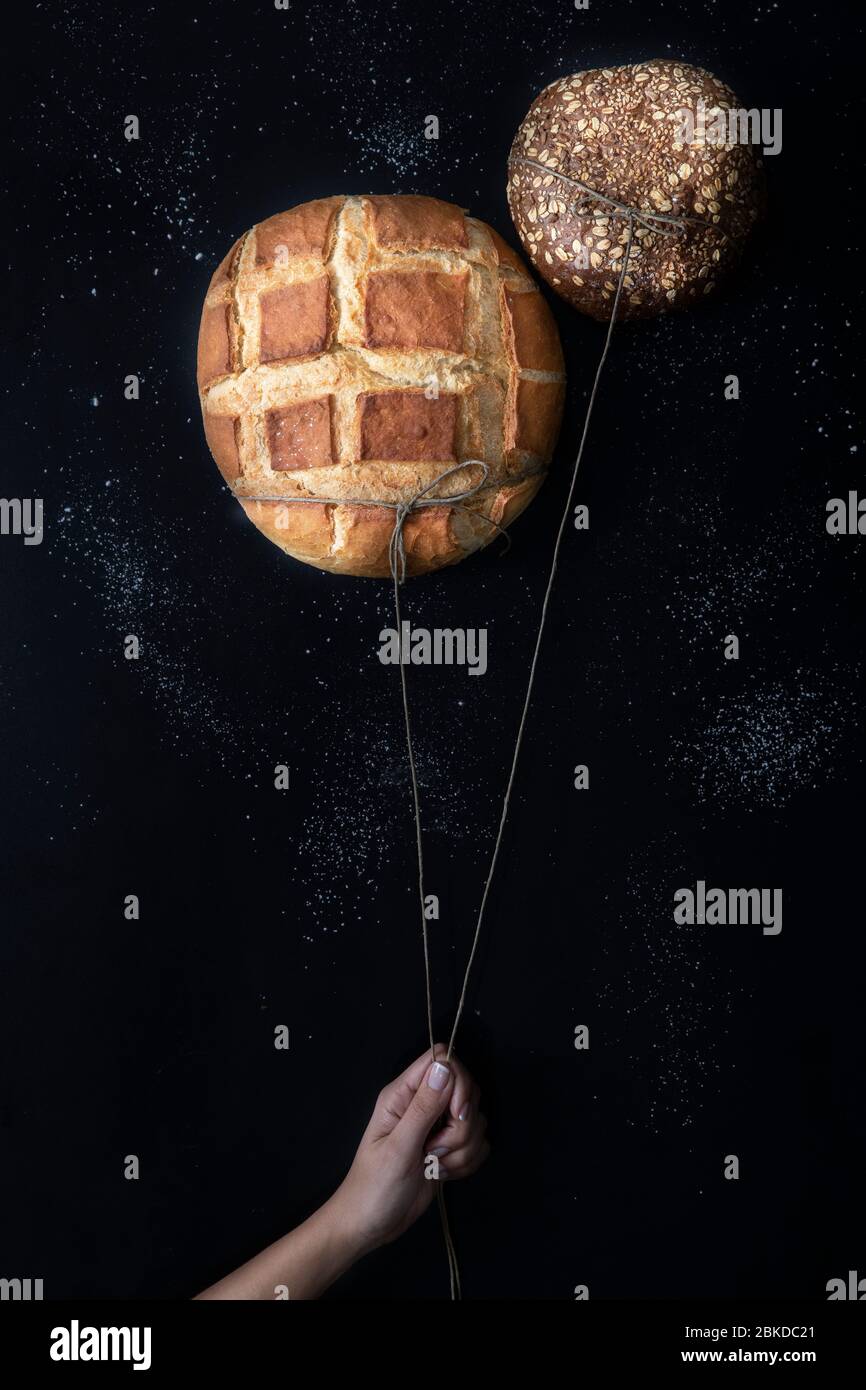 Zwei frische, knusprige Brote wie Luftballons am Himmel und Sterne aus Mehl auf schwarzem Hintergrund Stockfoto
