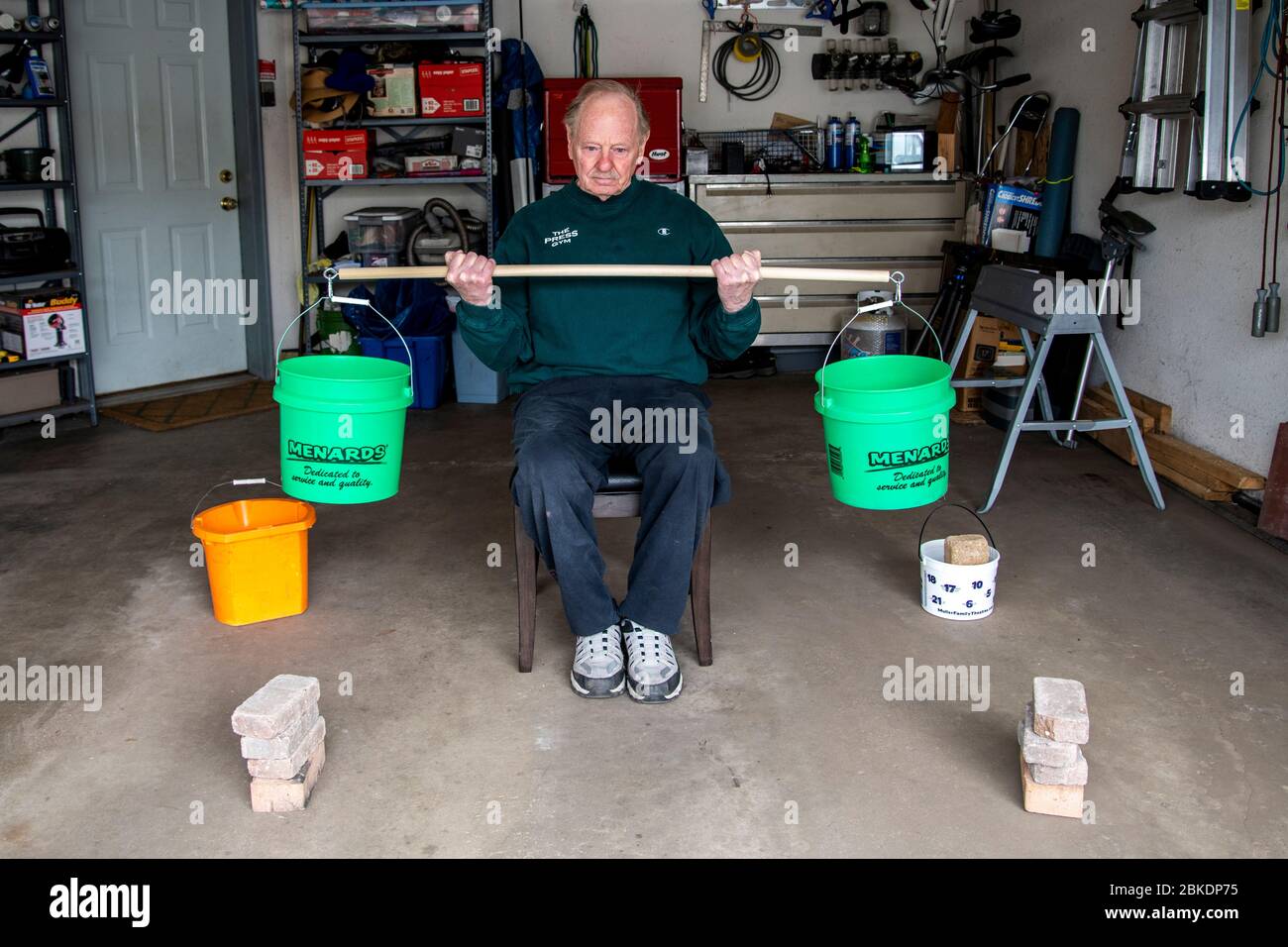 Vadnais Height, Minnesota. Ein Senior verwendet Eimer und Steine, um in seiner Garage zu trainieren, nachdem das Fitnessstudio wegen der Coronavirus-Pandemie geschlossen wurde. Stockfoto