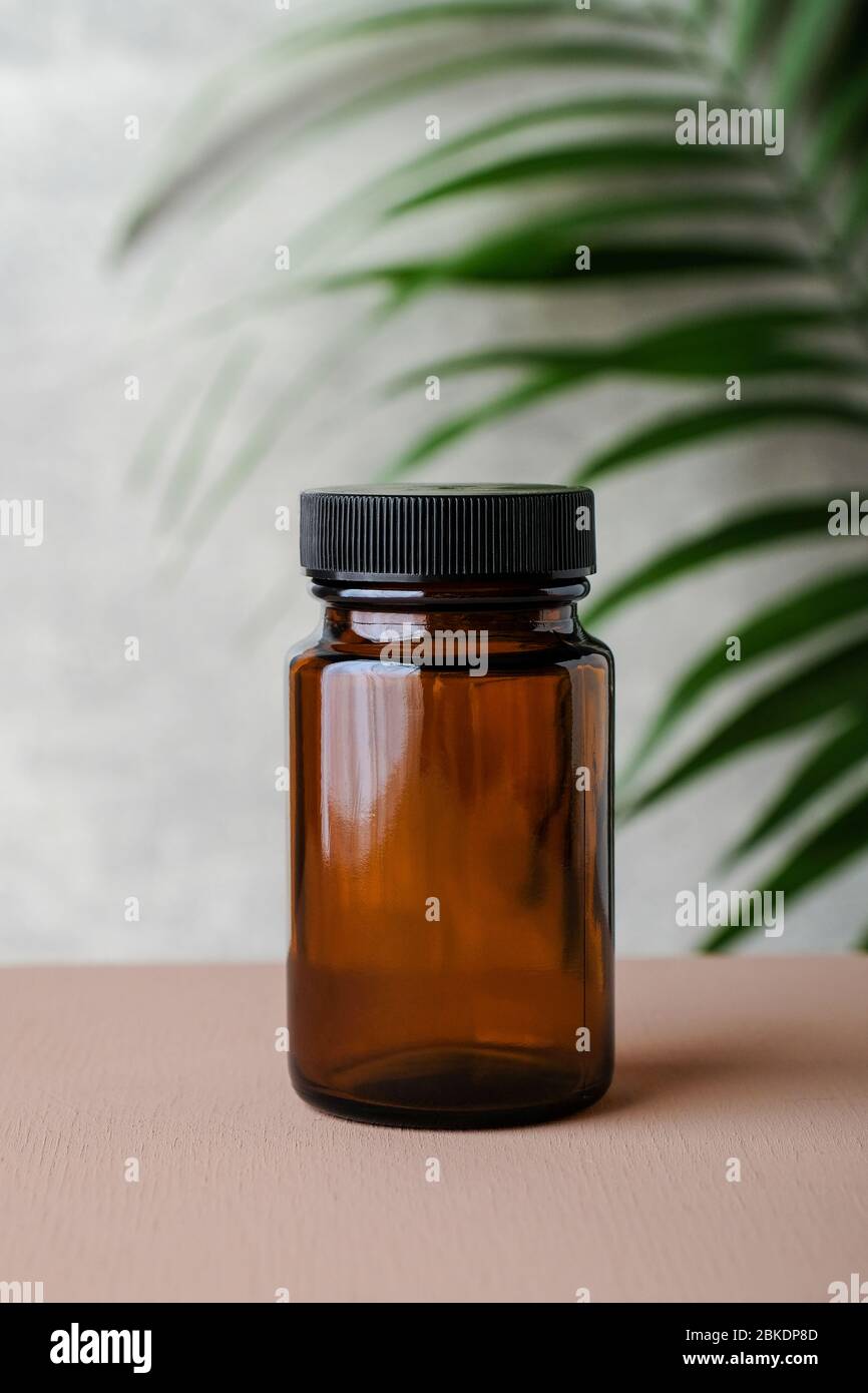Amber Glas Ergänzung Flasche und tropischen grünen Blatt. Medizinische Paket für Pillen, Kapsel, Medikamente. Konzept der Kräutermedizin. Stockfoto