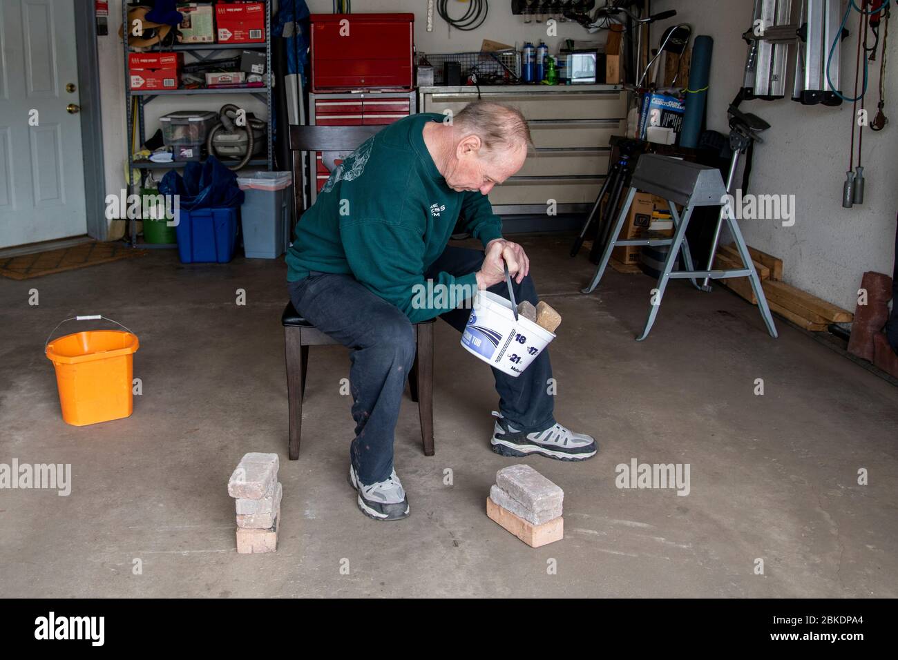 Vadnais Height, Minnesota. Ein Senior verwendet Eimer und Steine, um in seiner Garage zu trainieren, nachdem das Fitnessstudio wegen der Coronavirus-Pandemie geschlossen wurde. Stockfoto