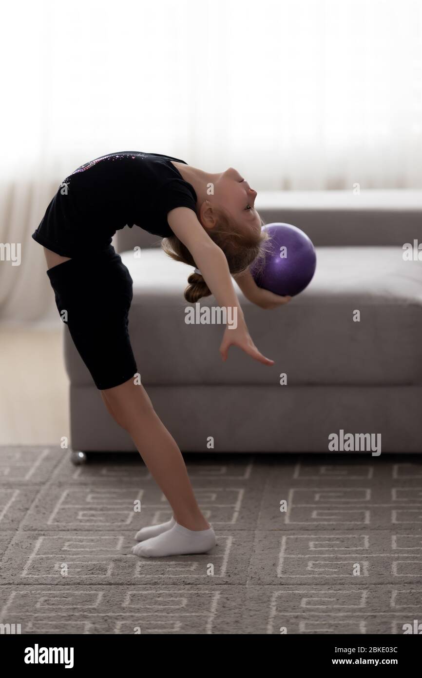 Übungen mit Gymnastikball. Kleines Mädchen führt gymnastische Tricks mit Ball Stockfoto