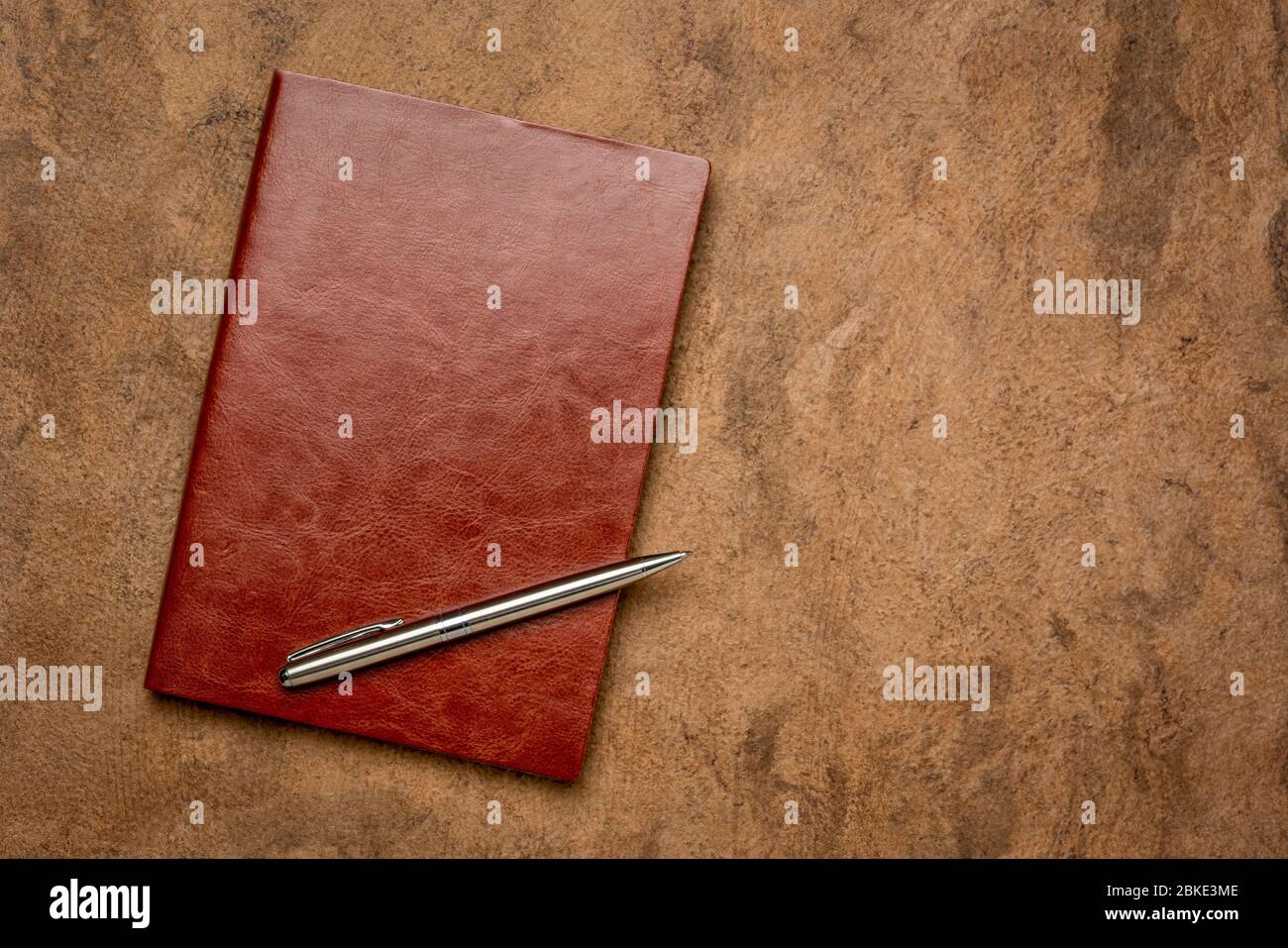 Tagebuch, Tagebuch oder Sammelalbum in einem reichen braunen Leder mit einem Metallstift auf handgeschöpftem strukturiertem Papier mit einem Kopierraum Stockfoto