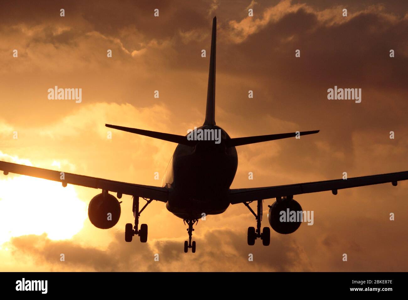 Flugreisen. Passagierflugzeug im Jet-Flugzeug, das bei Sonnenuntergang gegen einen bewölkten Himmel landet. Nahaufnahme von hinten in der Silhouette. Stockfoto