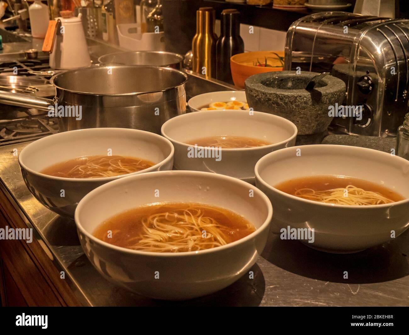 Nahaufnahme von Schalen von Ramen in einer Küche. Die Schalen mit Dashi-Brühe und Nudeln sind eine traditionelle japanische Mahlzeit. Stockfoto