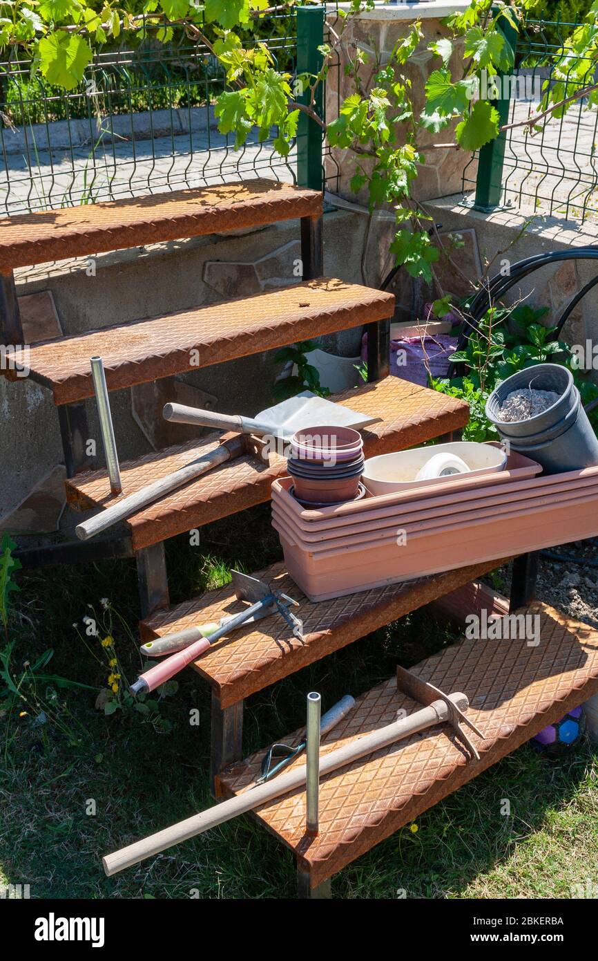 Gartengeräte Hacke, Pik, Töpfe auf rostigen Metall-Treppen Stockfoto