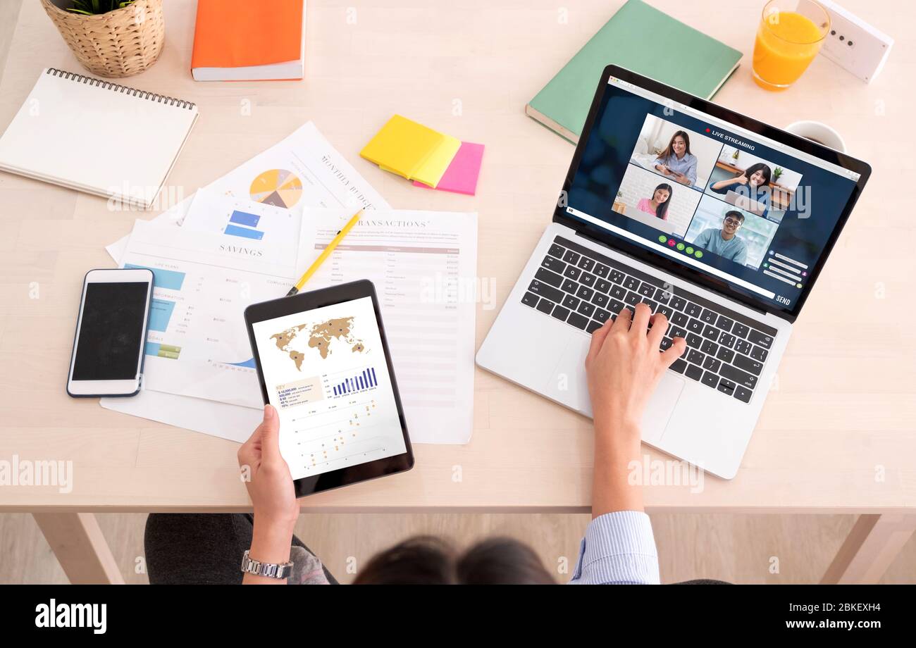asiatische Frau Arbeit von zu Hause aus mit Videokonferenz-App Zusammenarbeit mit Kollegen mit Business Chart auf Tablet.Live-Streaming meeting.protect Risiko o Stockfoto