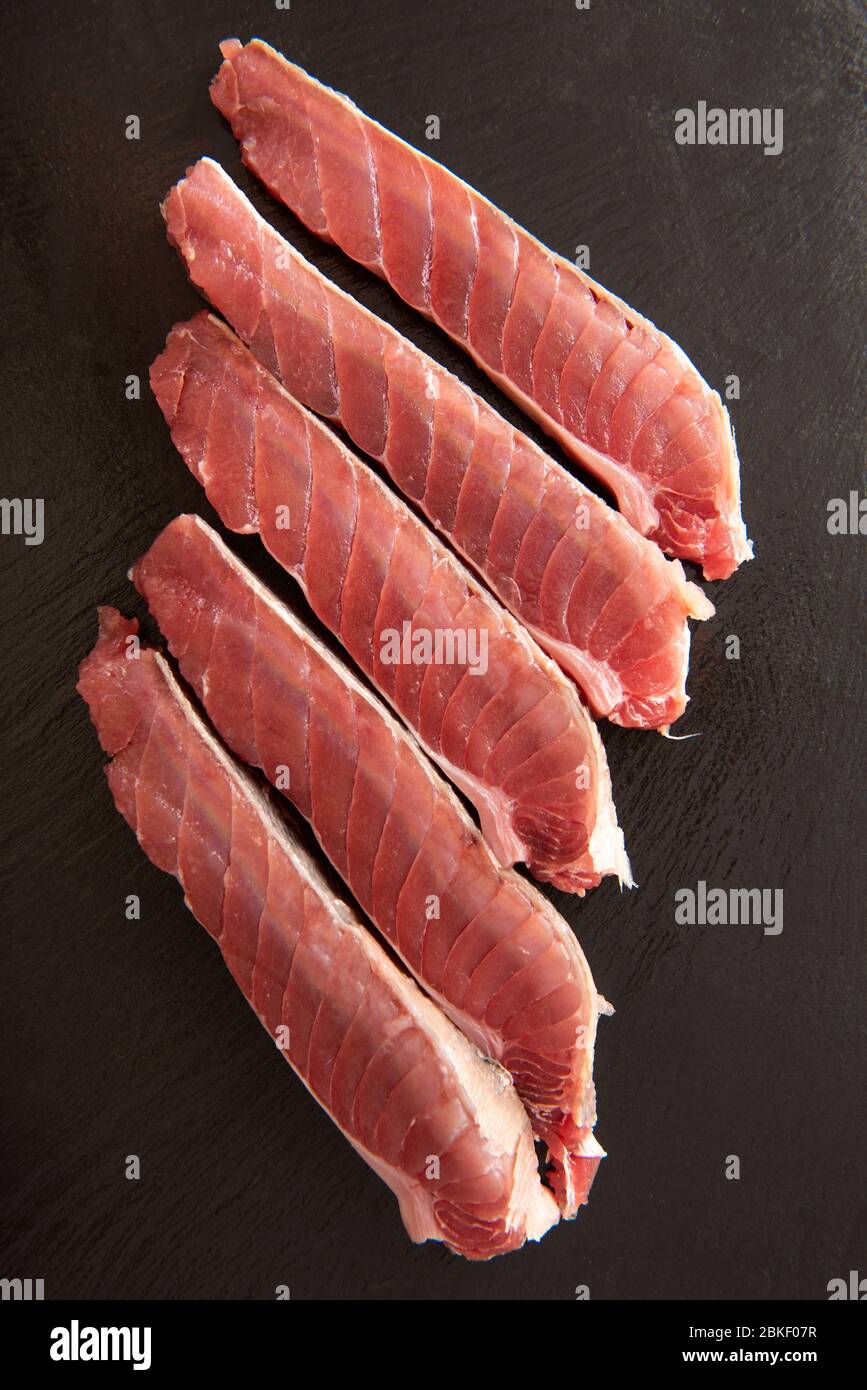 Scheiben von frischem Thunfisch mit grobem Salz auf schwarzem Hintergrund. Stockfoto