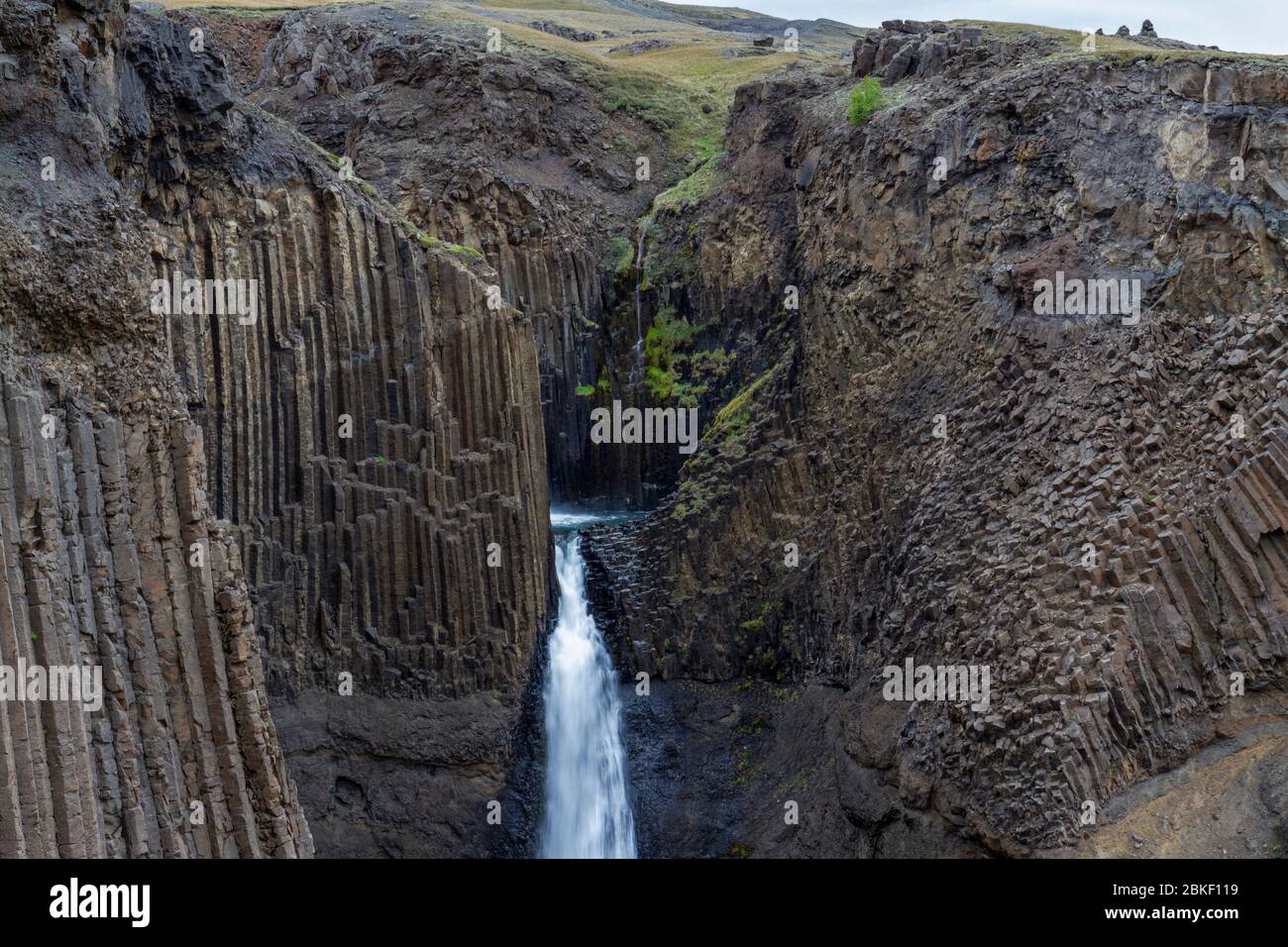 Der atemberaubende Wasserfall Litlanesfoss, wo das Wasser zwischen massive Basaltsäule Geologie fällt, Island. Stockfoto