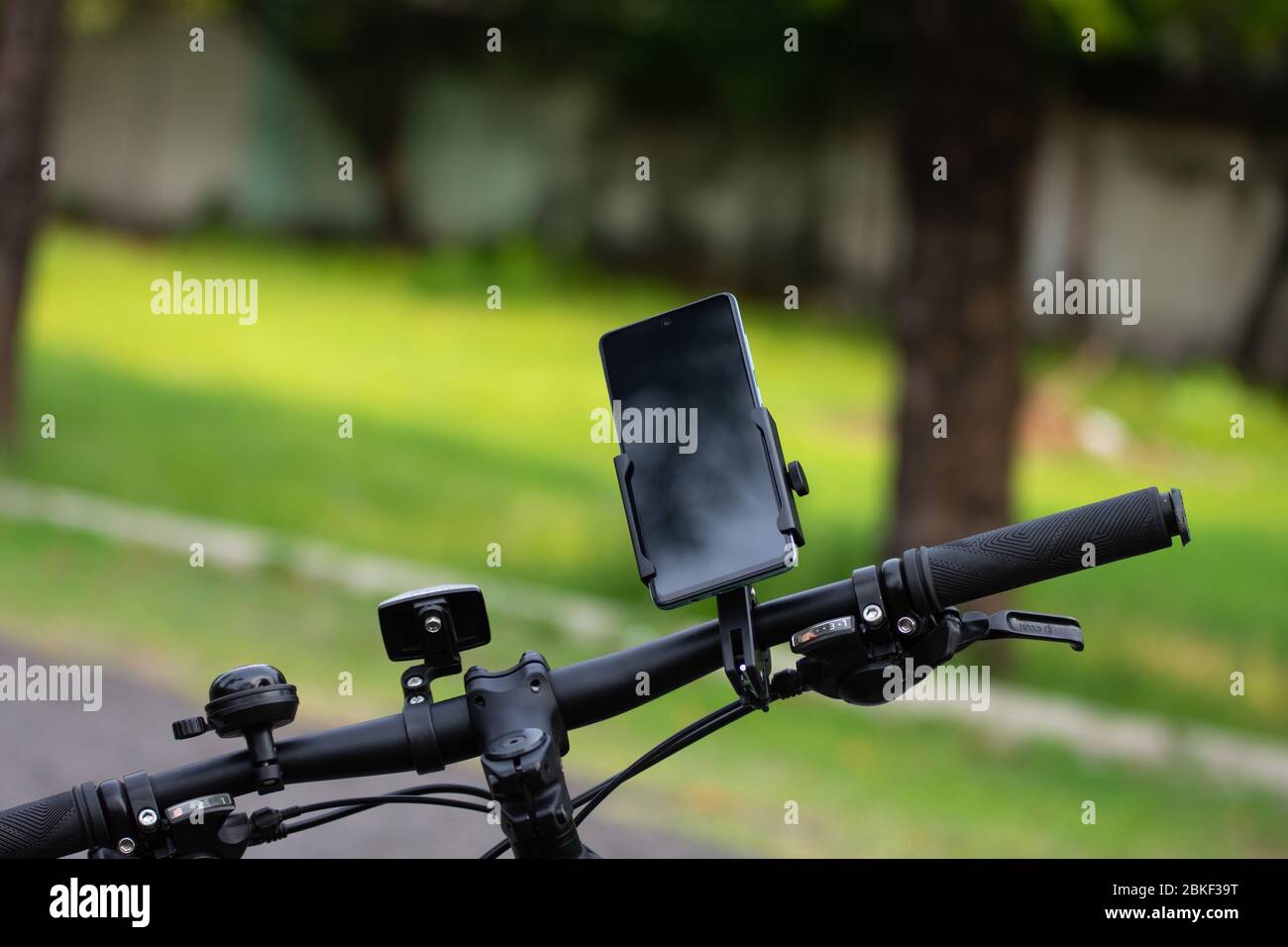 Smartphone auf Halteregal am Lenker des Fahrrads auf verschwommenem Hintergrund befestigt. Stockfoto