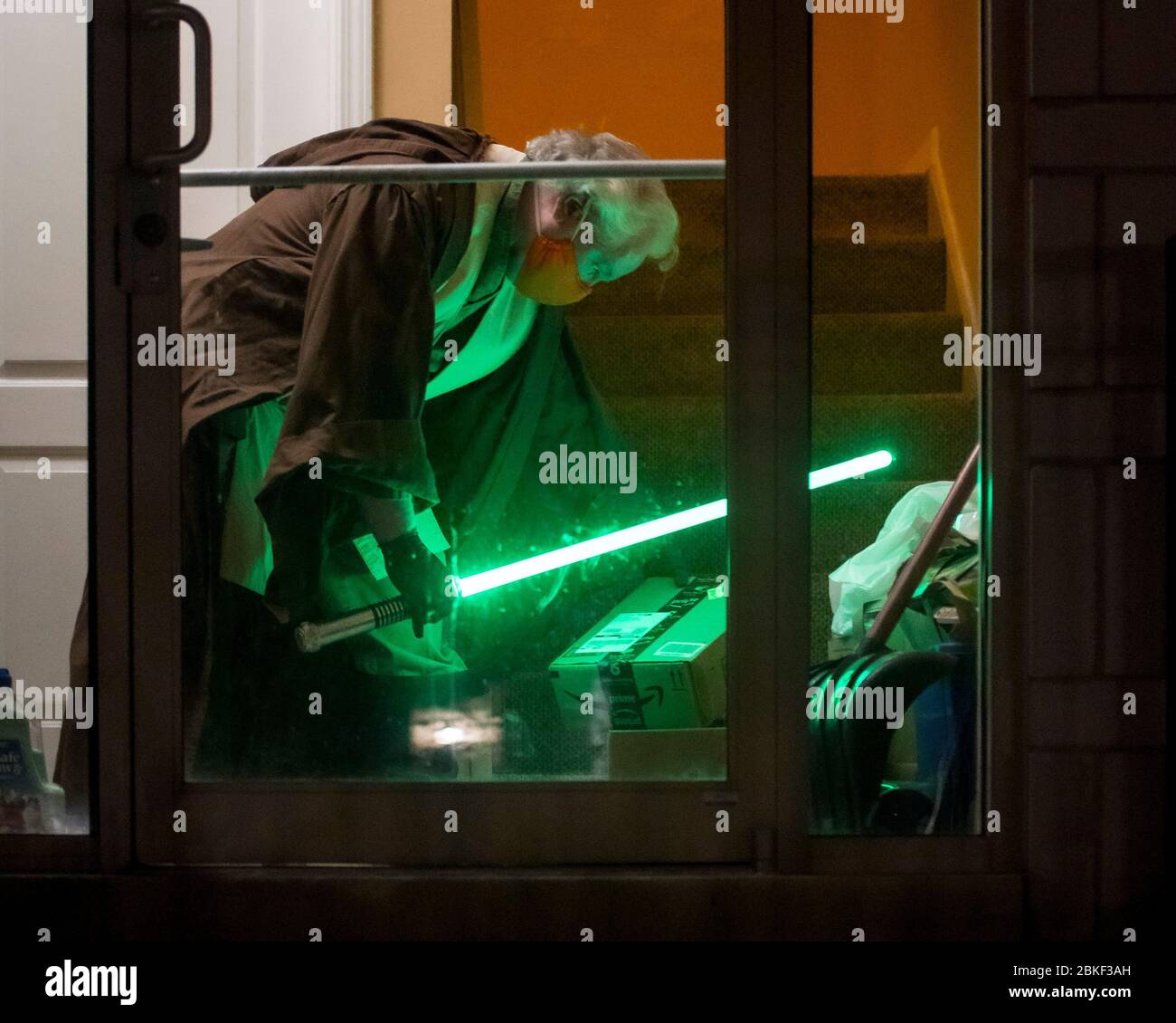 Chicago, Illinois, USA. Mai 2020. Jedi-Botschafter der Chicago Jedi, DAN MCCANN, 56, inspiziert ein Amazon-Paket, das mit seinem Lichtschwert in der Lobby geliefert wird. ''die soziale Distanzierung hat die Dinge verlangsamt. Es hat uns einige unserer Servicemendienungen erschwert und uns verschiedene Lösungswege einfallen lassen.“ Der jährliche Charity Run der Chicago Jedi in diesem Jahr musste abgesagt werden, ebenso wie ihre Scheinlichtbaber-Schlacht und Trainingskurse. Kredit: Chris Riha/ZUMA Wire/Alamy Live News Stockfoto