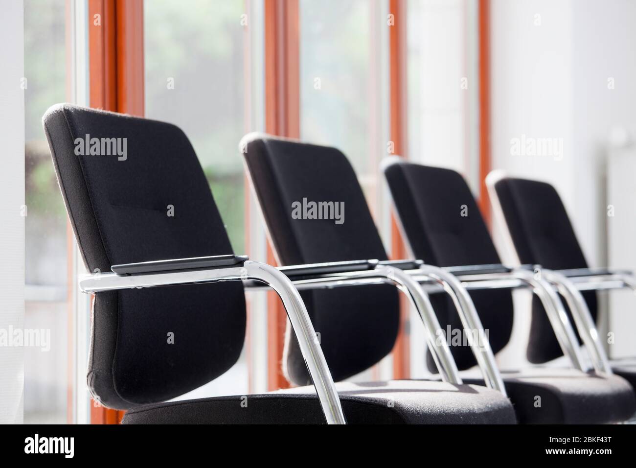 Stühle in einer Reihe in einem sonnigen Warteraum oder Lounge - konzentrieren Sie sich auf die Armlehne des ersten Stuhls Stockfoto