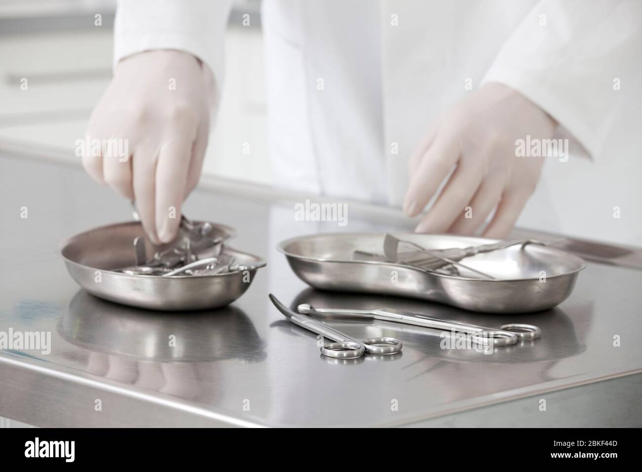 Hände einer Krankenschwester, die medizinische Instrumente nimmt - Fokus auf die Schere im Vordergrund Stockfoto