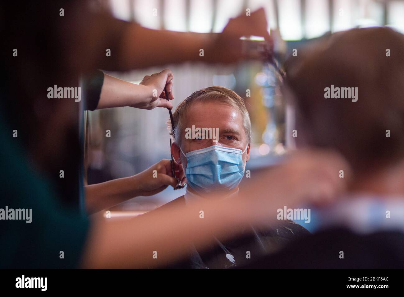 Magdeburg, Deutschland. Mai 2020. Doreen Mewes vom Friseursalon 'Hairlounge  Falke' wäscht mit einem Mundschutz die Haare einer ihrer Kunden, während  sich ihr Haar in einem Spiegel spiegelt. Die Friseure wurden am Morgen
