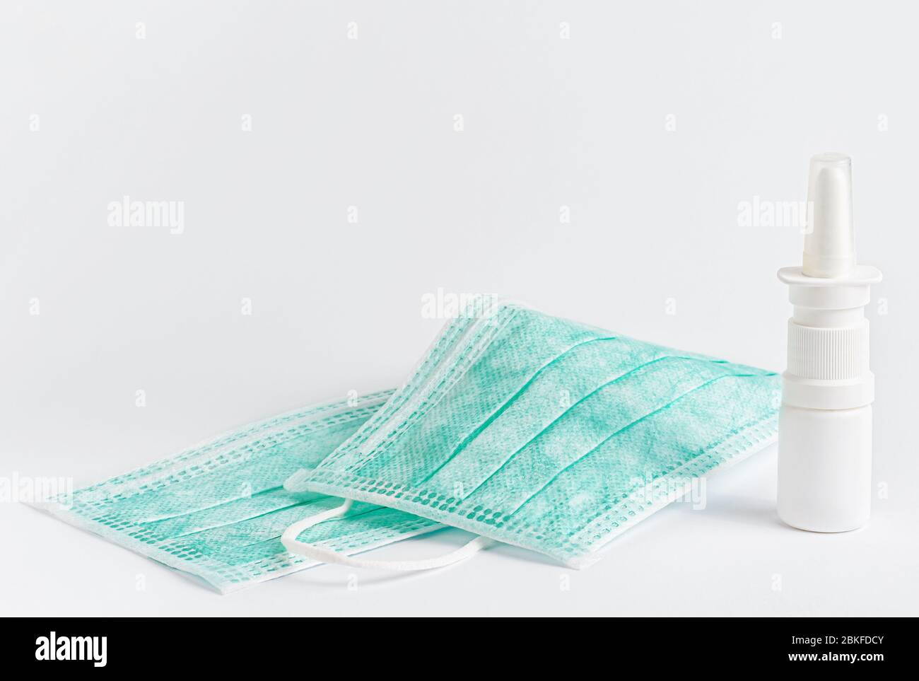 Medizinische Schutzmaske und Nasenspray auf weißem Hintergrund. Kopierbereich. Stockfoto