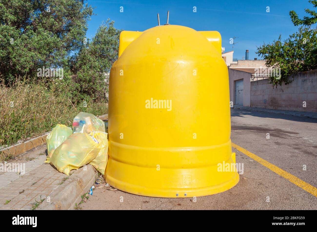 Campos, Balearen/Spanien; Mai/03/2020: Gelber Kunststoff-Recycling-Container mit Tüten aus Kunststoff, die auf den Boden geworfen werden Stockfoto