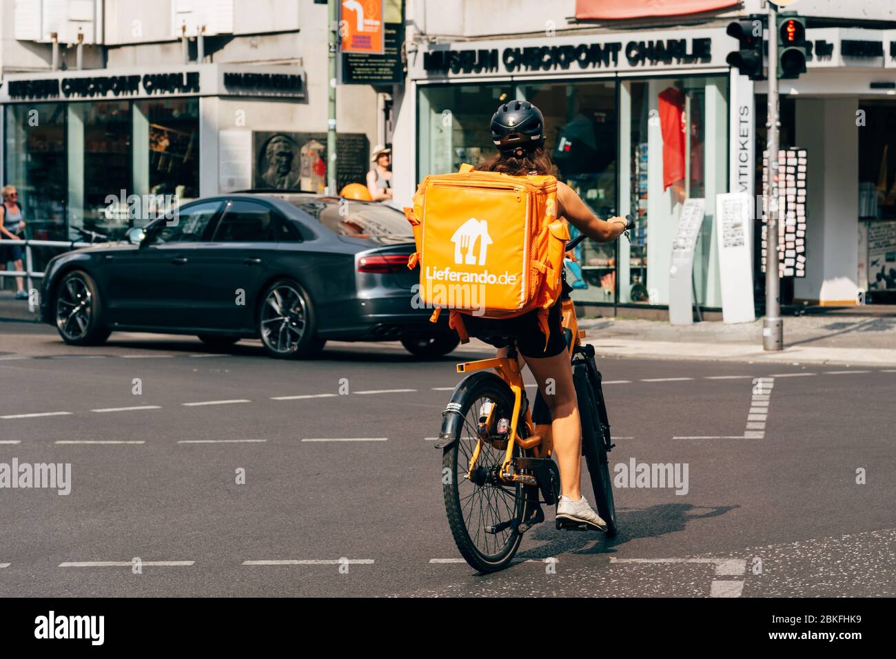 Berlin, Deutschland - 29. Juli 2019: Junge Frau auf dem Fahrrad auf der Friedrichstraße, die Lebensmittel für Lieferando, einen deutschen Lebensmittellieferdienst, liefert Stockfoto