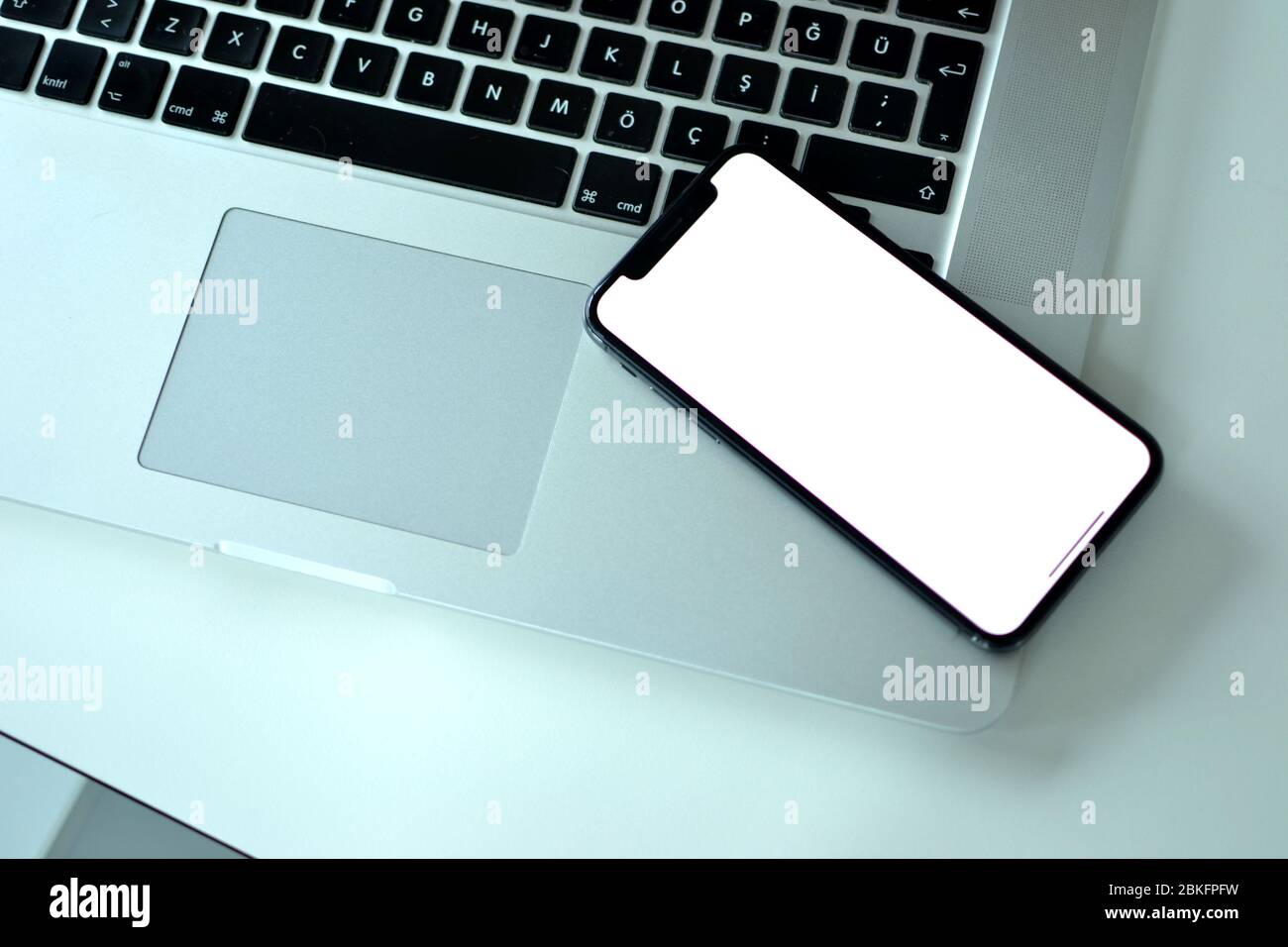 Auf einem MacBook Pro befindet sich ein Apple iPhone XS auf dem Schreibtisch. Es ist üblich für Menschen mit Apple-Produkte sowohl für Mobiltelefone und Laptops. Stockfoto