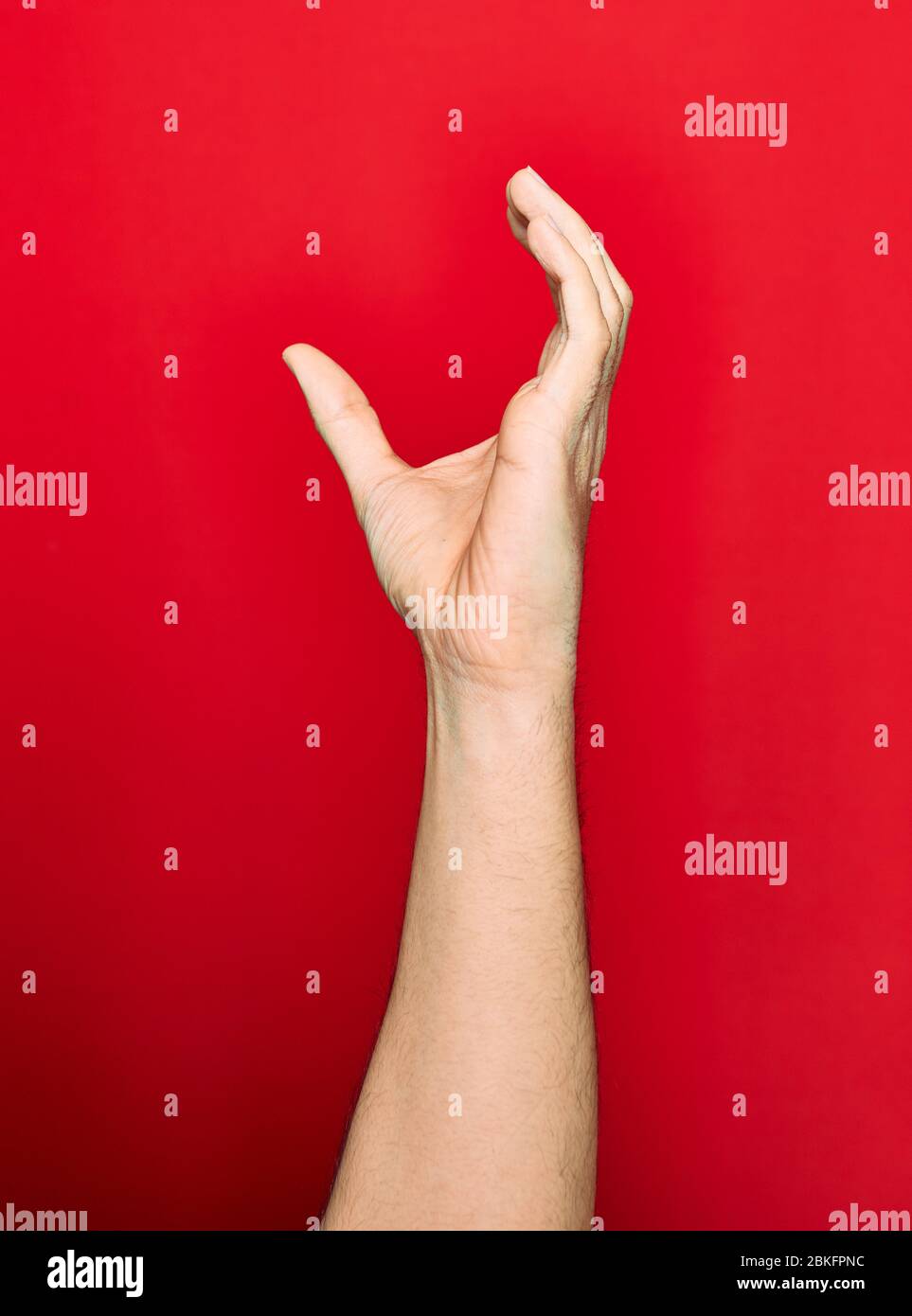 Schöne Hand des Mannes zeigt Finger angehoben tun fangen Geste über isolierten roten Hintergrund Stockfoto