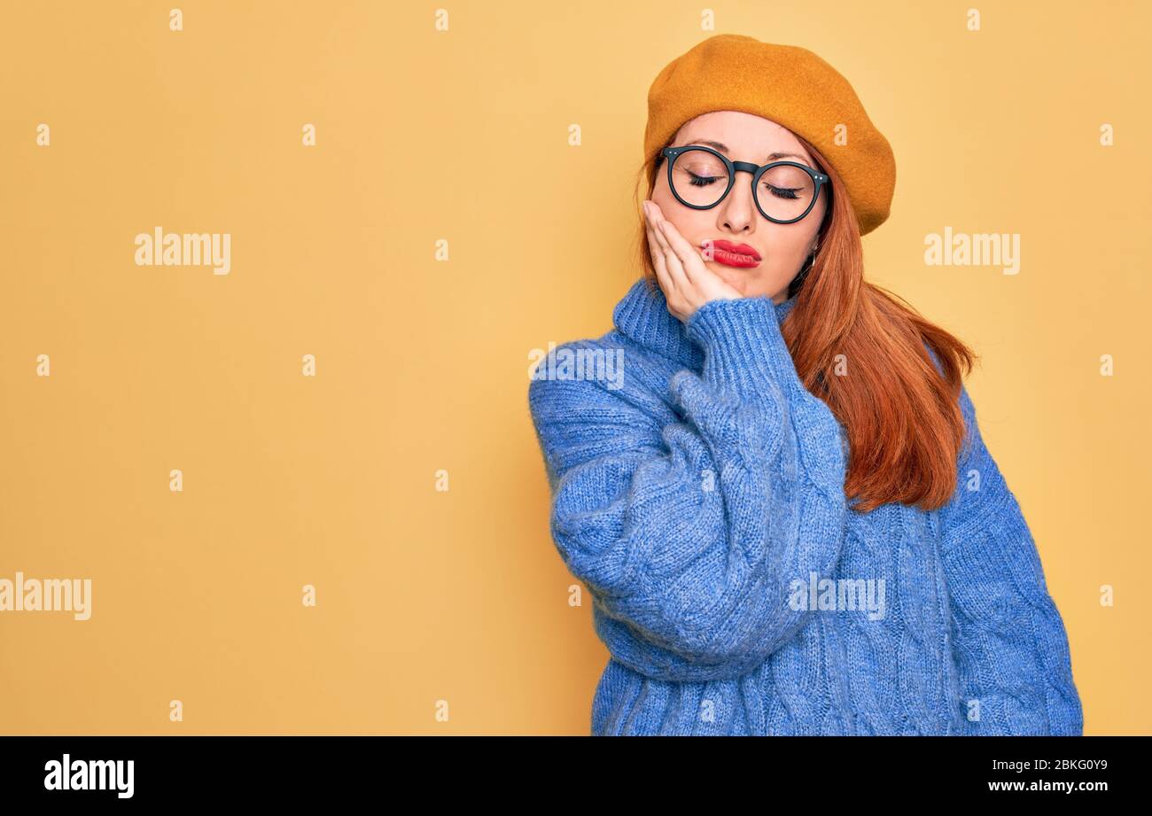Junge schöne Rotschopf Frau trägt französisch Baskenmütze und Brille über  gelben Hintergrund denken müde und gelangweilt mit Depression Probleme mit  c Stockfotografie - Alamy