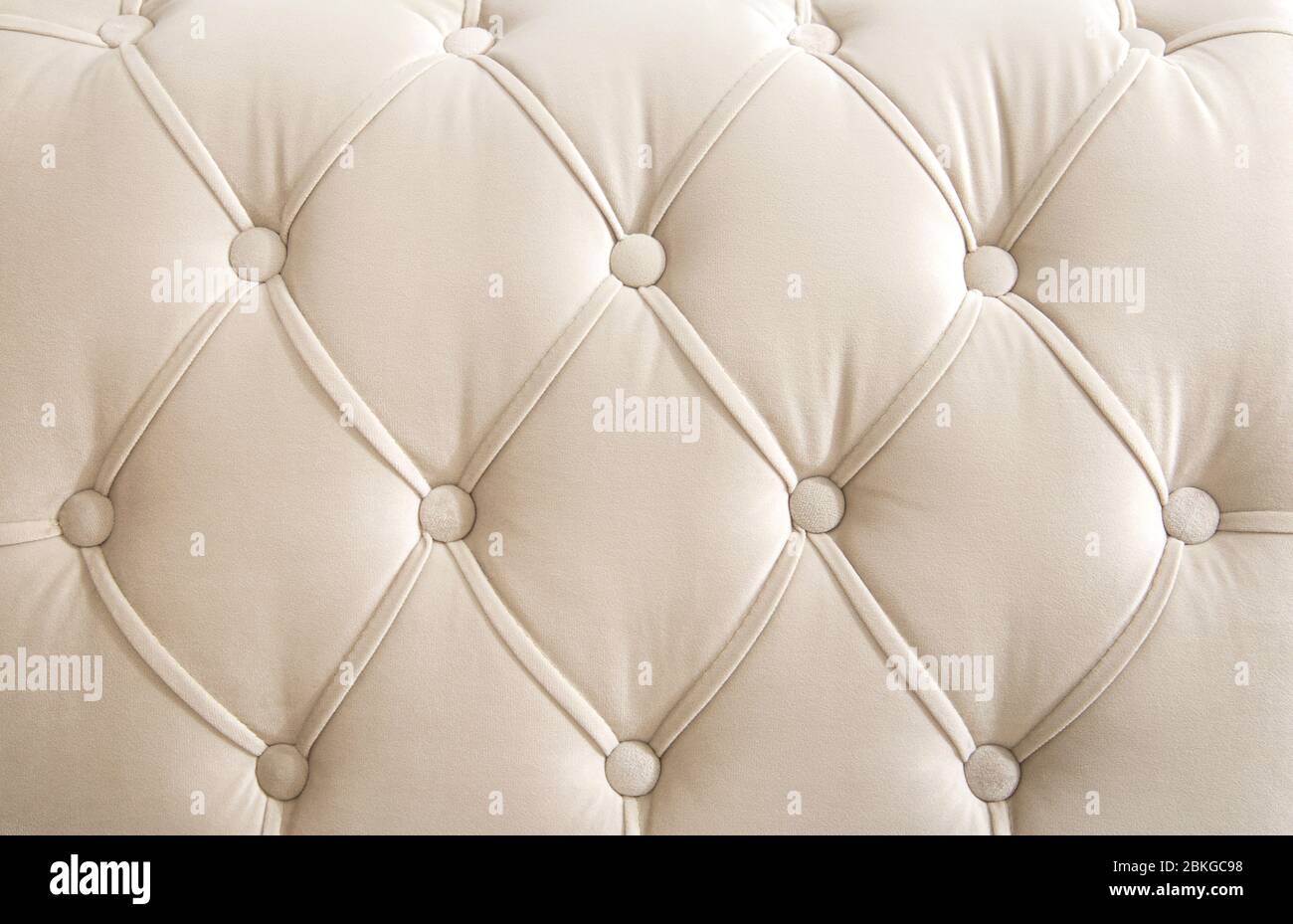 Hellbeige Velours Textil-Rautenmuster mit Knöpfen. Hintergrundkonzept. Möbel Sofa Abdeckung. Stockfoto