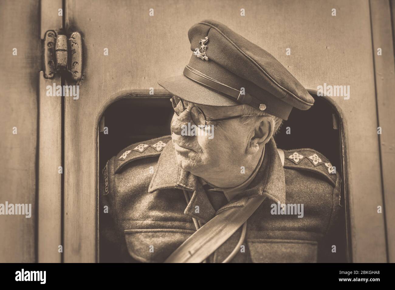 Sepia Nahaufnahme von 1940er Mann als Home Guard Offizier Captain Mainwaring (Arthur Lowe lookalike) Blick aus dem alten Zugfenster Severn Valley Railway. Stockfoto