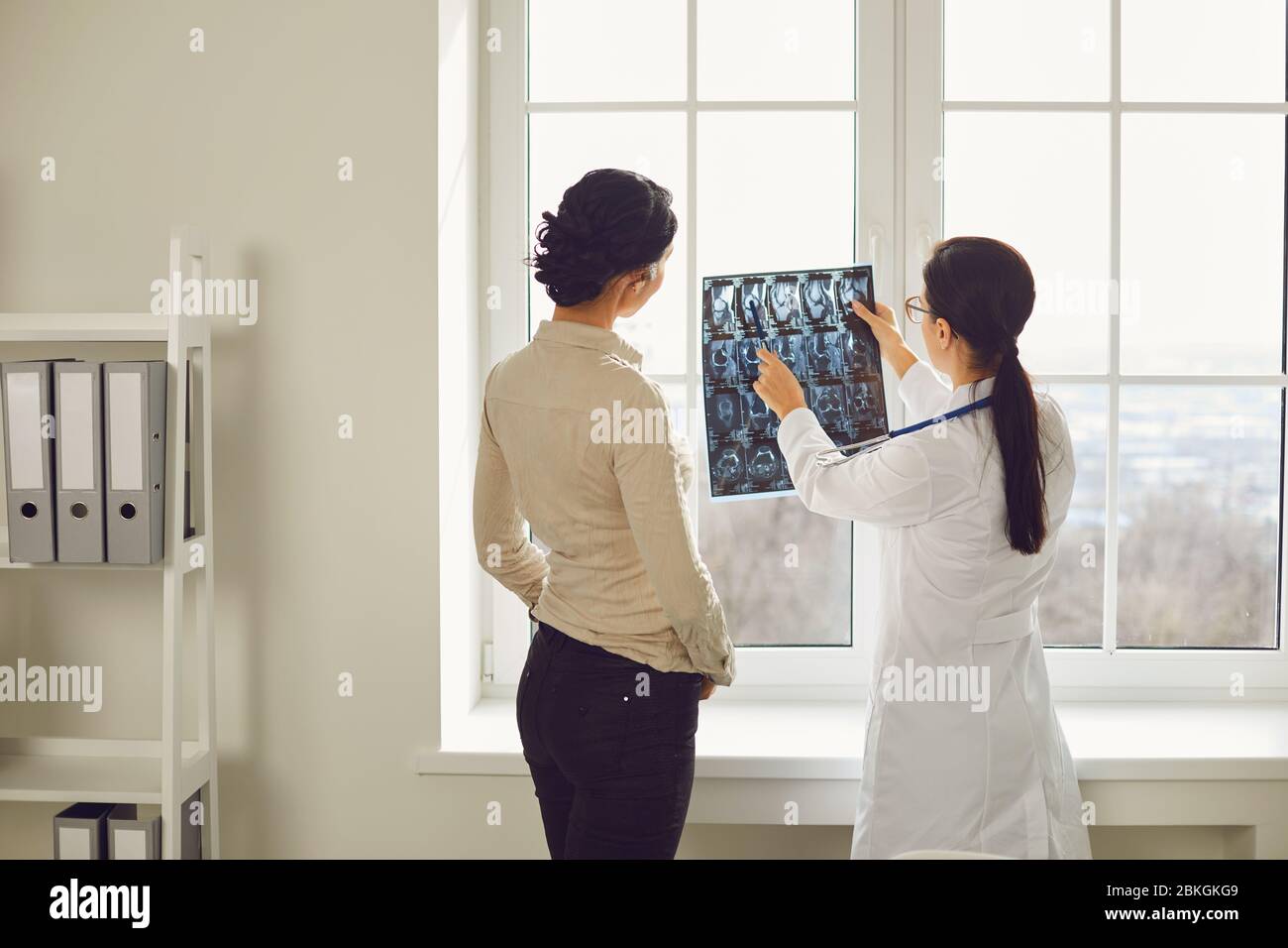 Ärztin mit Röntgensprecherin sitzt an einem Tisch in einem Klinikbüro. Stockfoto