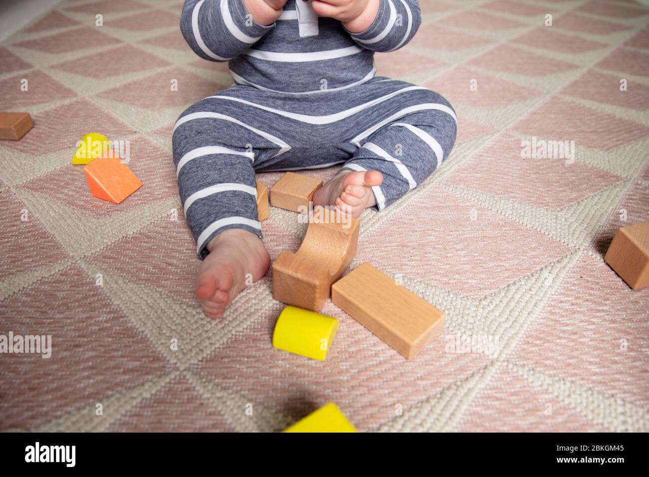 Ein Kleinkind, das mit hölzernen Spielblöcken in ihrem Kindergarten spielt, schoss von oben Stockfoto
