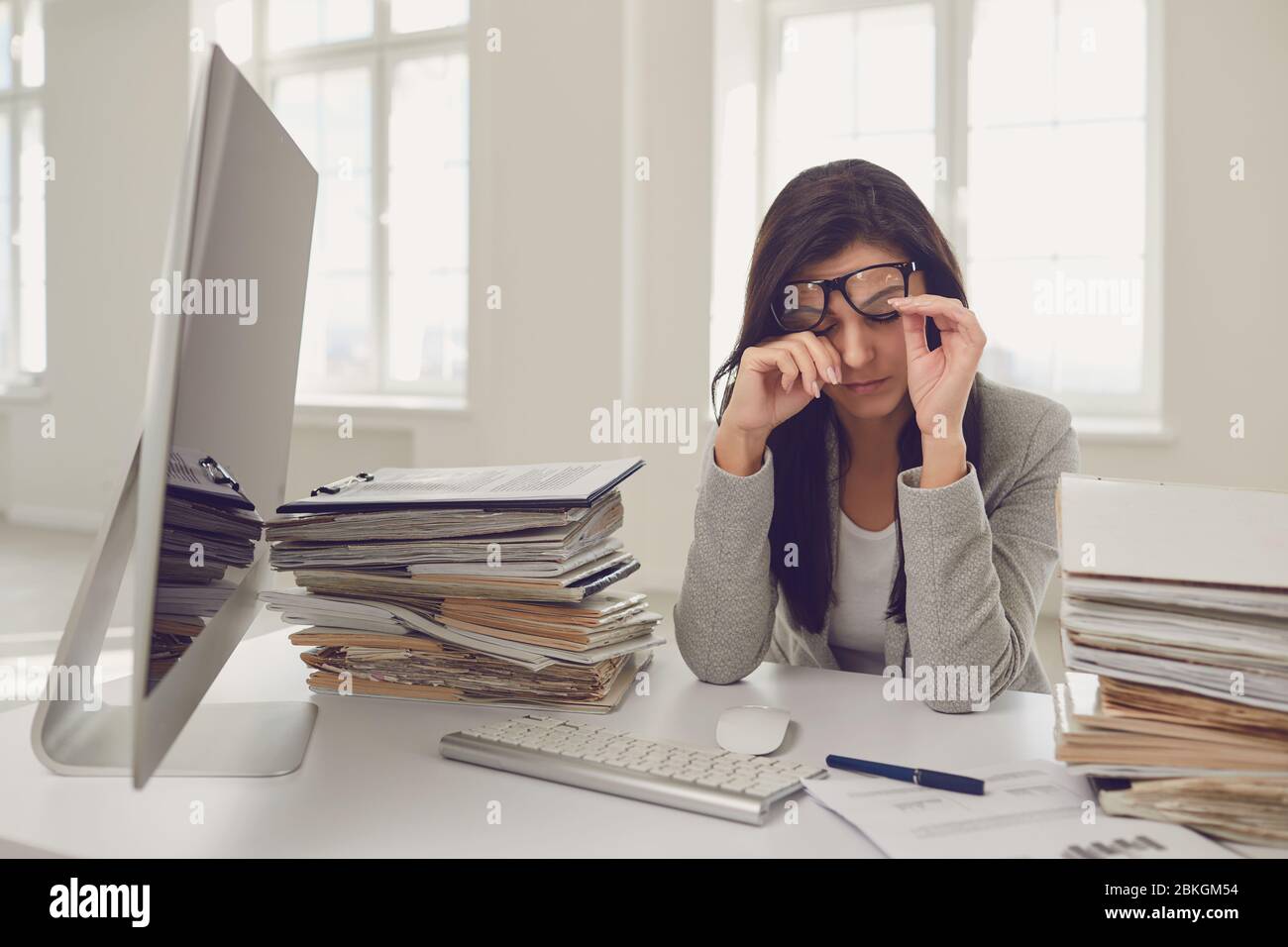 Viel Arbeit im Büro. Müde beschäftigt Geschäftsfrau arbeitet mit Computer. Stockfoto