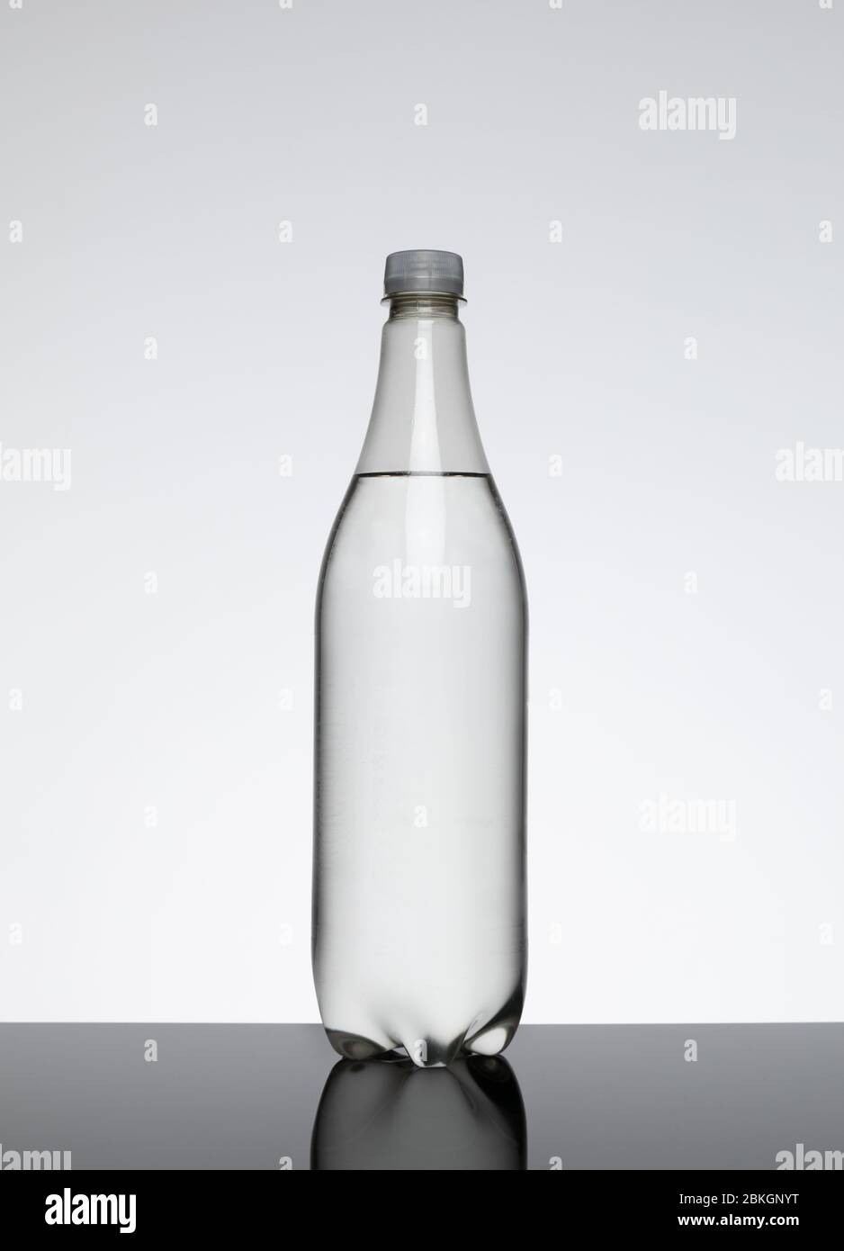 Eine 1-Liter-Plastikflasche ohne Etikett, das eine klare Flüssigkeit vor einem einfachen Hintergrund enthält Stockfoto